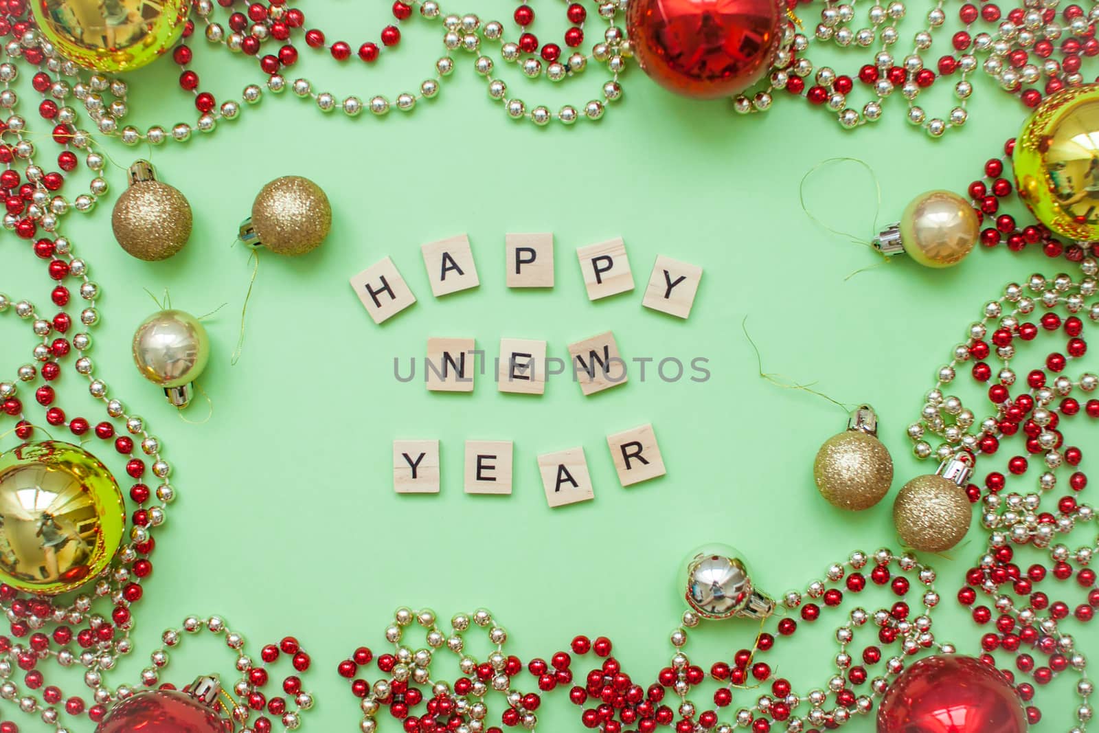inscription happy new year in a Christmas frame of gold and red balls and beads on a green background