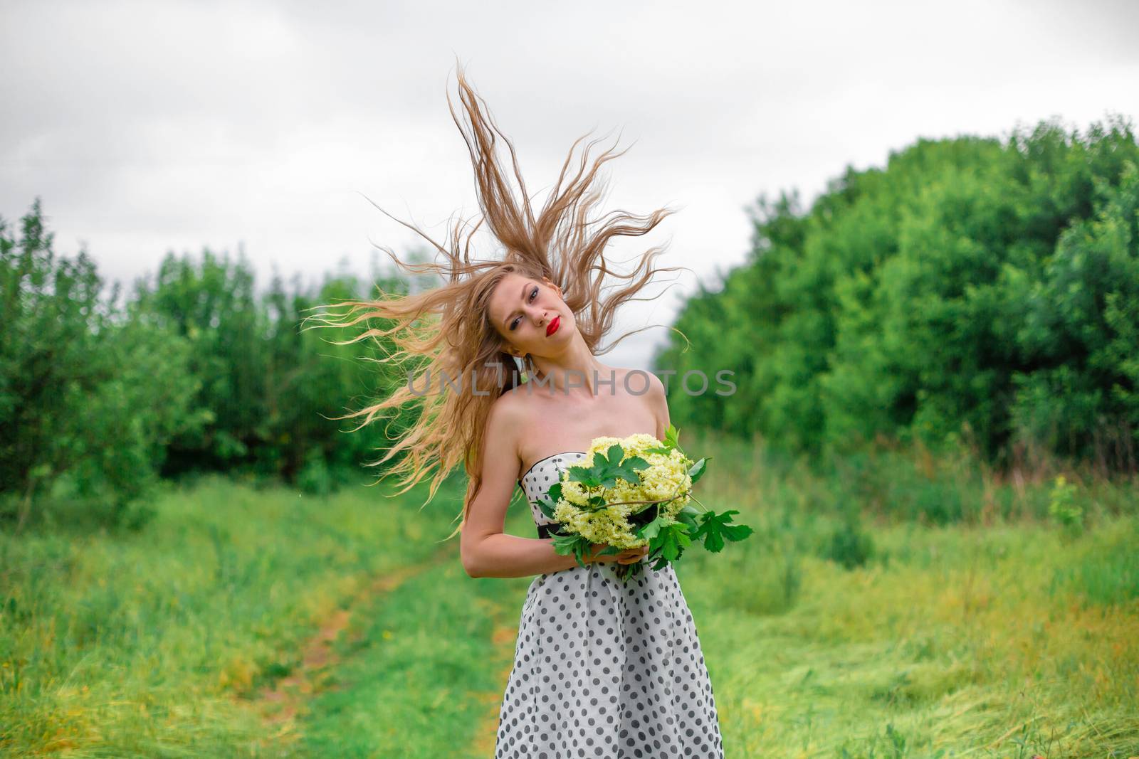 A beautiful young blonde girl collected a bouquet of wildflowers. Enjoy a walk on a warm summer day.