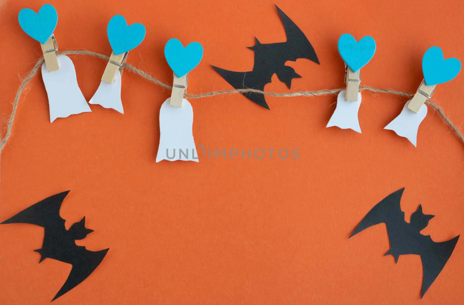 The concept of Halloween. Halloween decorations, pumpkins, bats, ghosts on clothespins with blue hearts on an orange background. Flat bed, top view text space by lapushka62