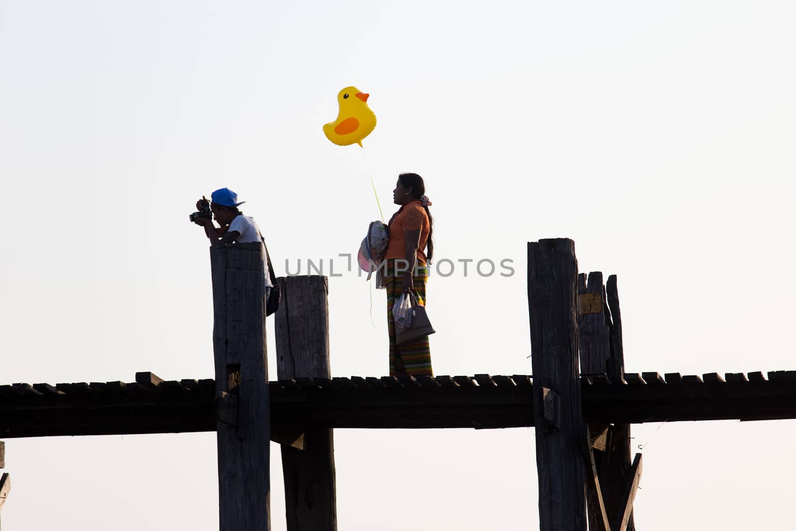 Woman holding balloon of duck on u bien bridge over Taungthaman Lake near Amarapura Mandalay Myanmar. High quality photo