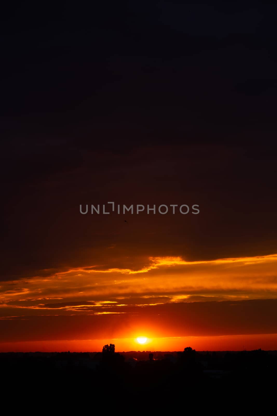 Heavy cloudy sky at sunset. Orange line of light between black clouds. A landscape of beautiful nature.