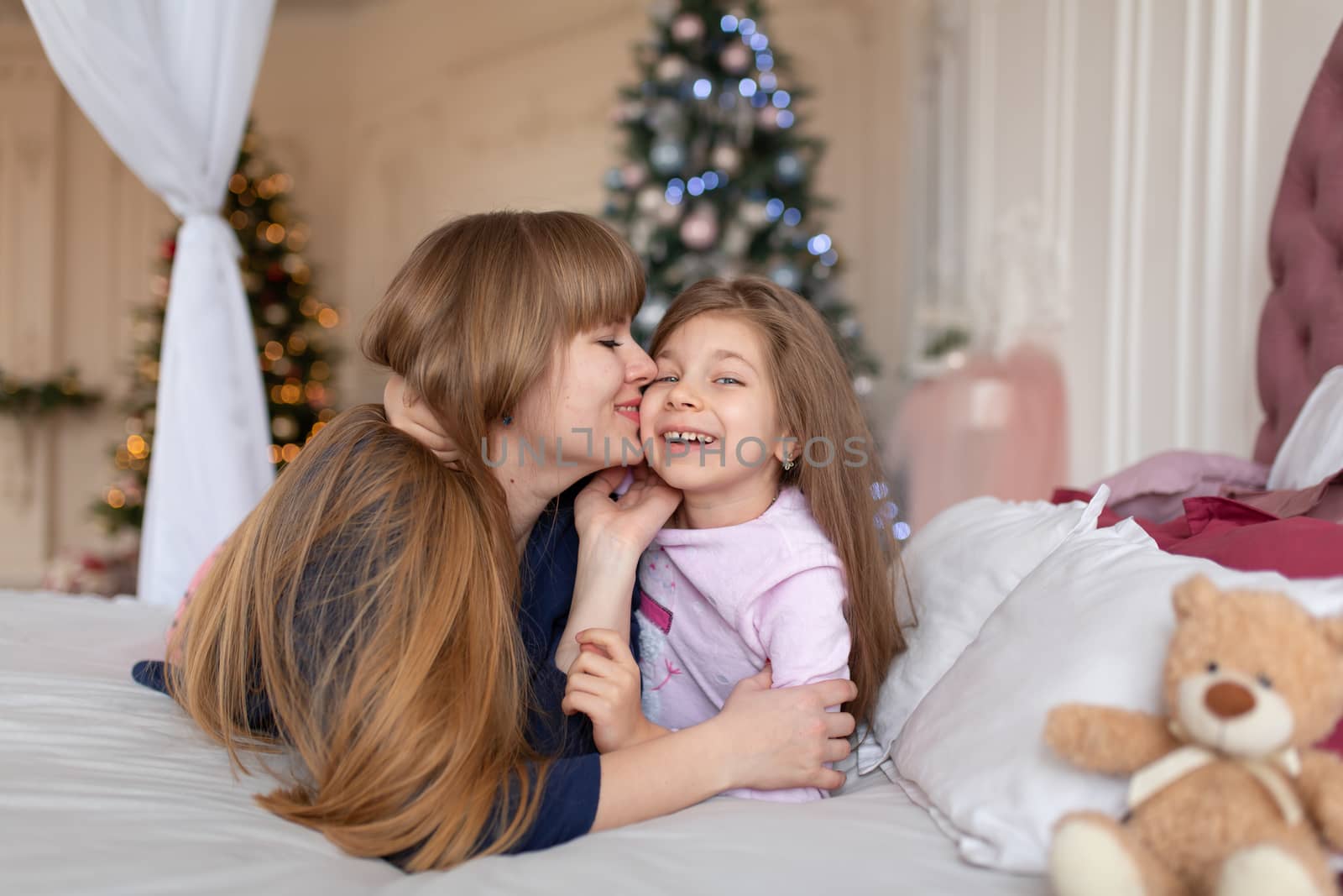 Little girl spends time playing with mom while lying in bed. Christmas tale. Happy childhood.