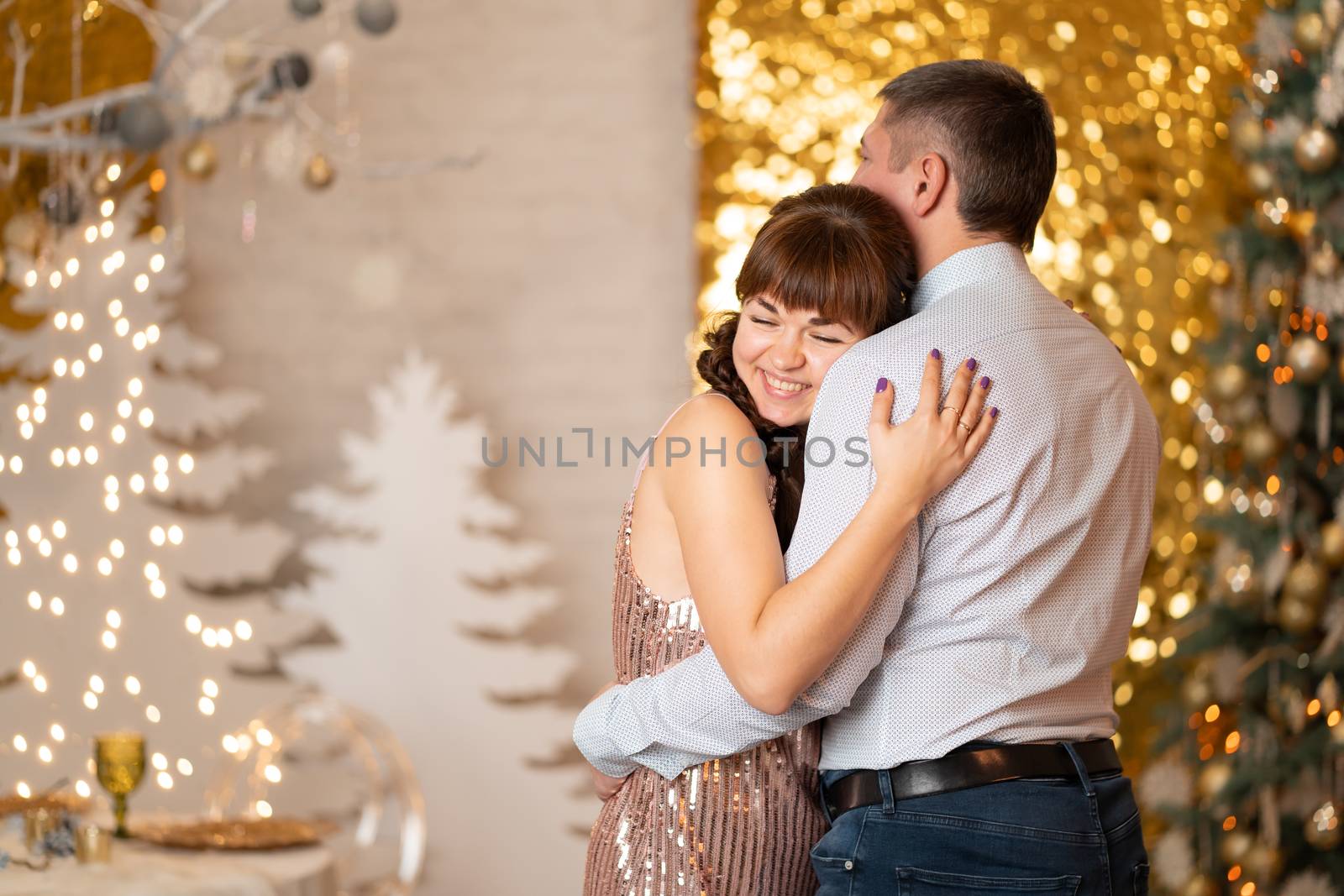 A joyful girl hugs a guy among sparkles and gerlands at a Christmas party by Try_my_best