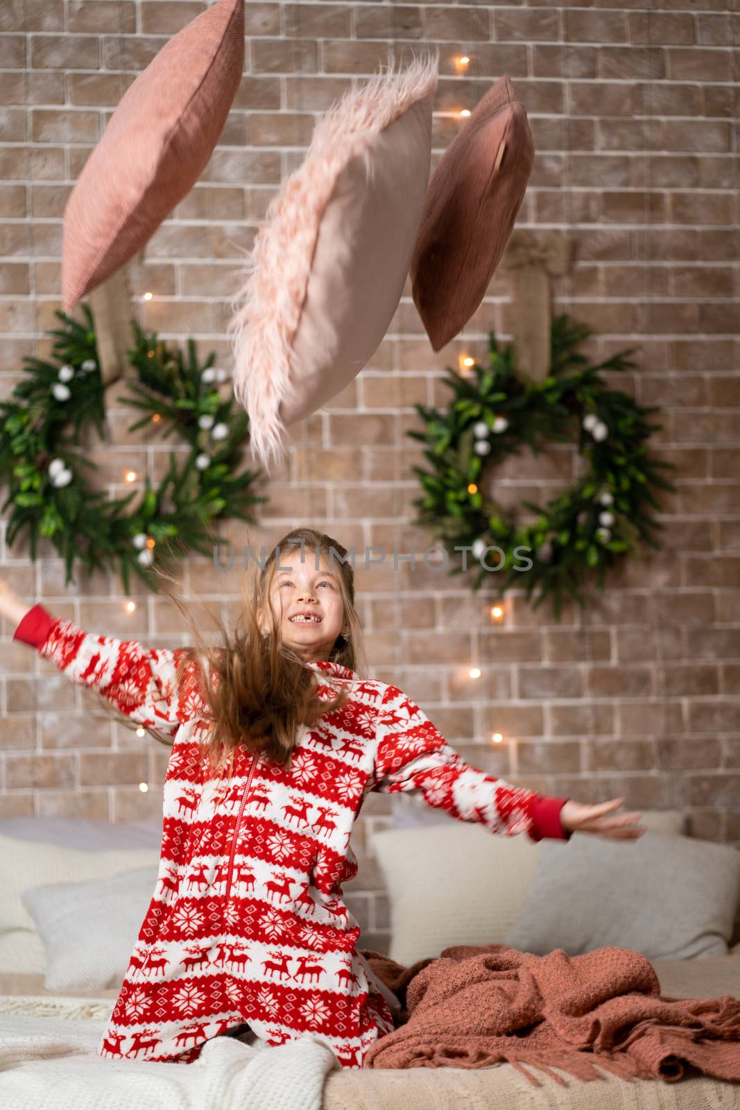 Little girl throws pillows on the sofa.