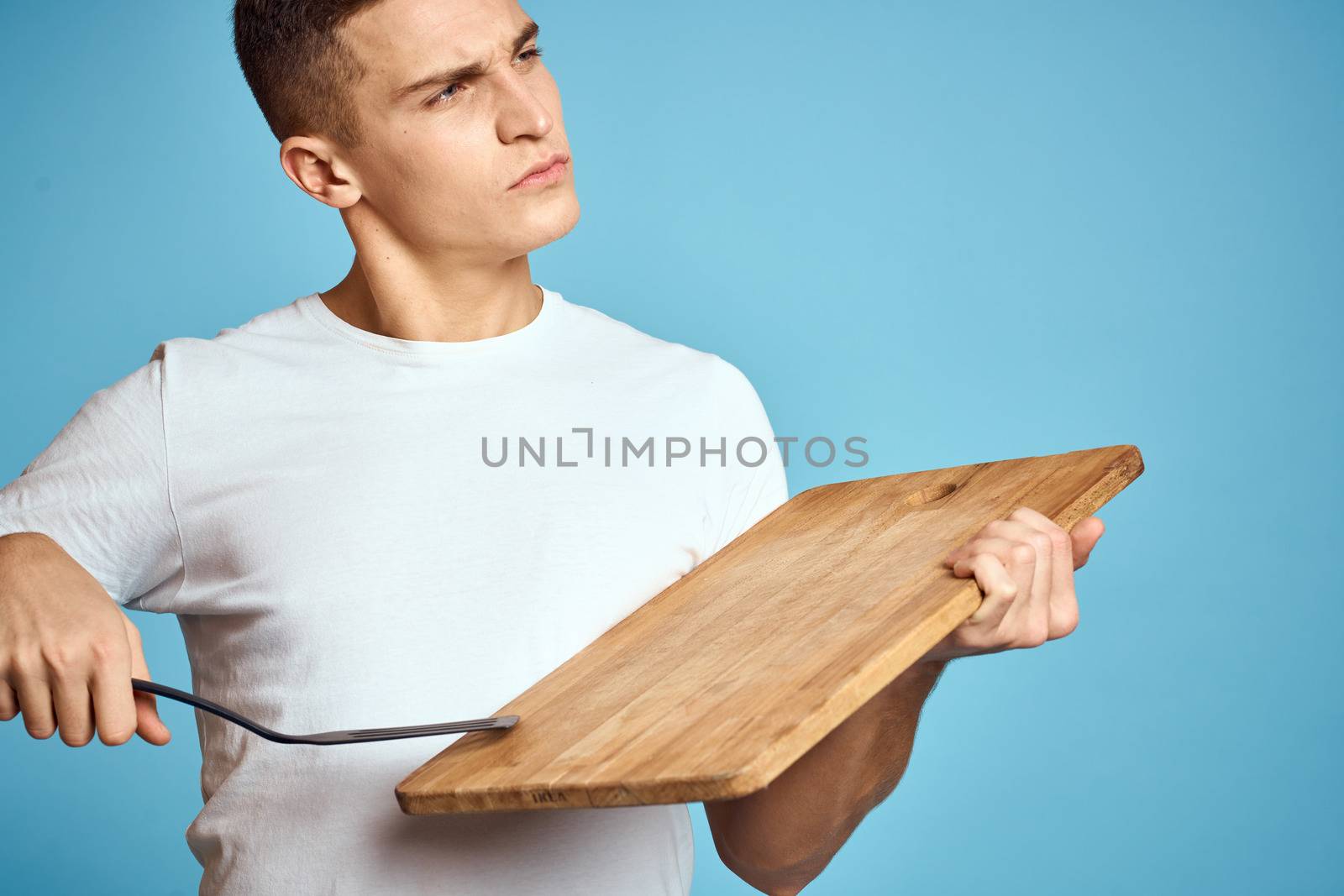 energetic guy with wooden kitchen board and spatula fun emotions. High quality photo