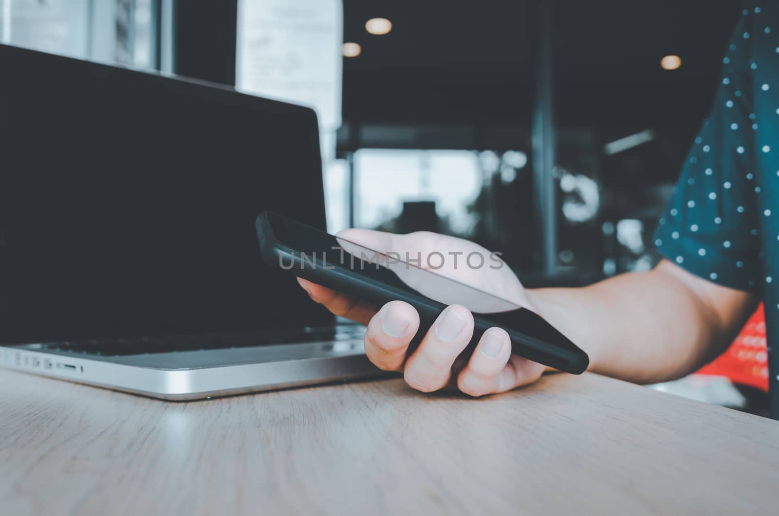 business man holding a cell phone looking at work data and laptop computers on the desk at the office.business and technology concept