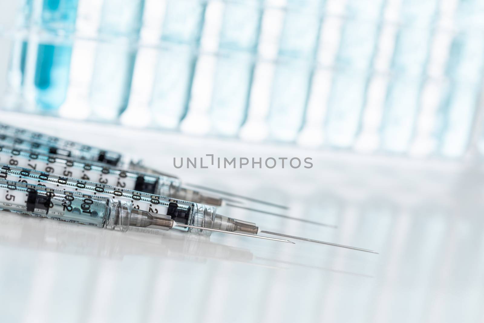 Abstract of Scientific Needle Syringes and Test Tubes Containing Blue Chemical In Rack.