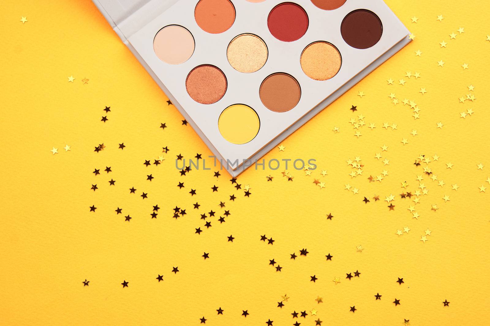 Eyeshadow palette on a yellow background and different colors of cosmetics. High quality photo