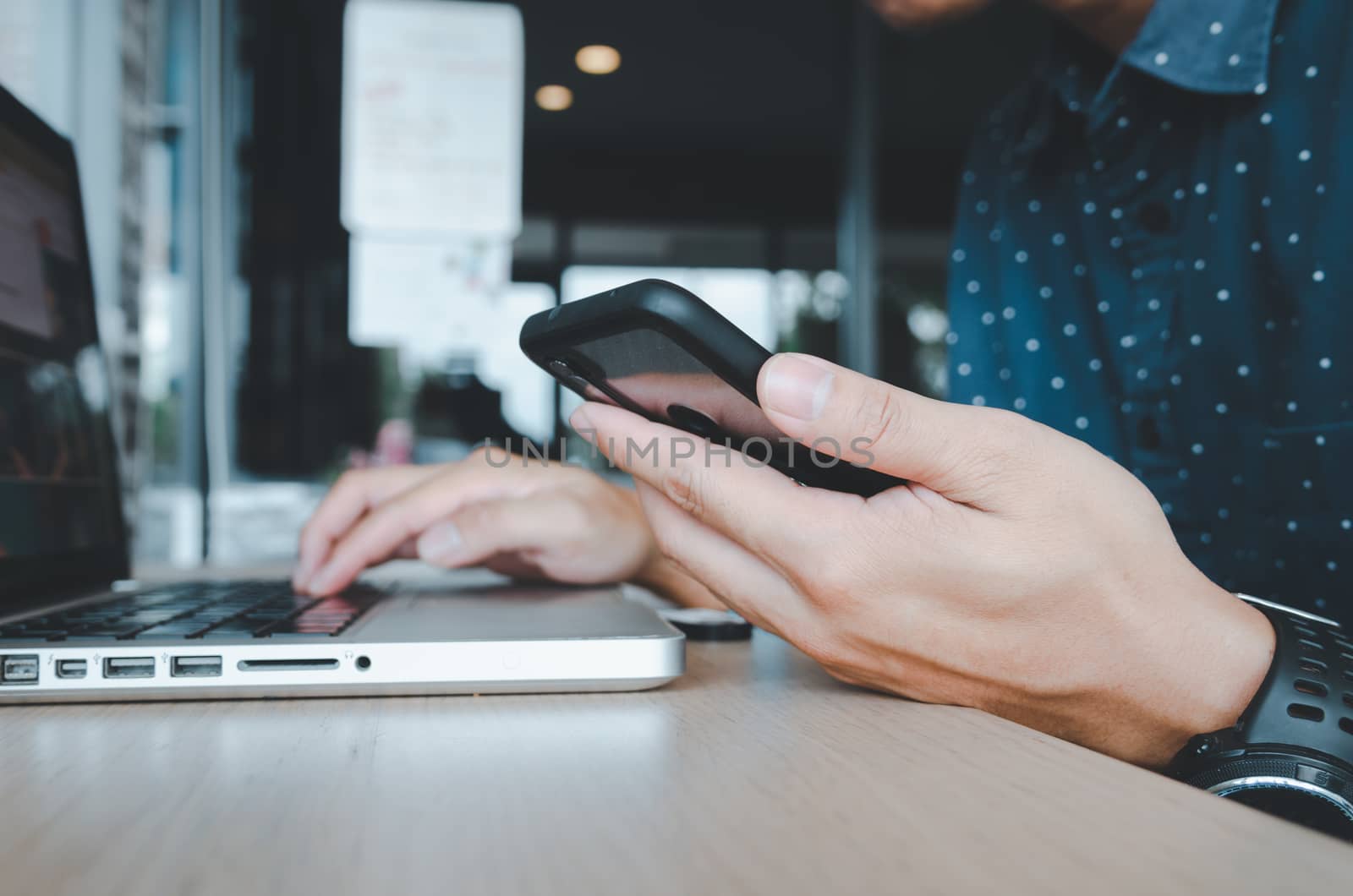 Man holding a cell phone and a laptop at a desk  by aoo3771