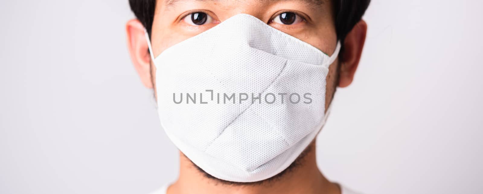 Closeup Asian handsome Man wearing surgical hygienic protective cloth face mask against coronavirus, studio shot isolated white background, COVID-19 medical concept