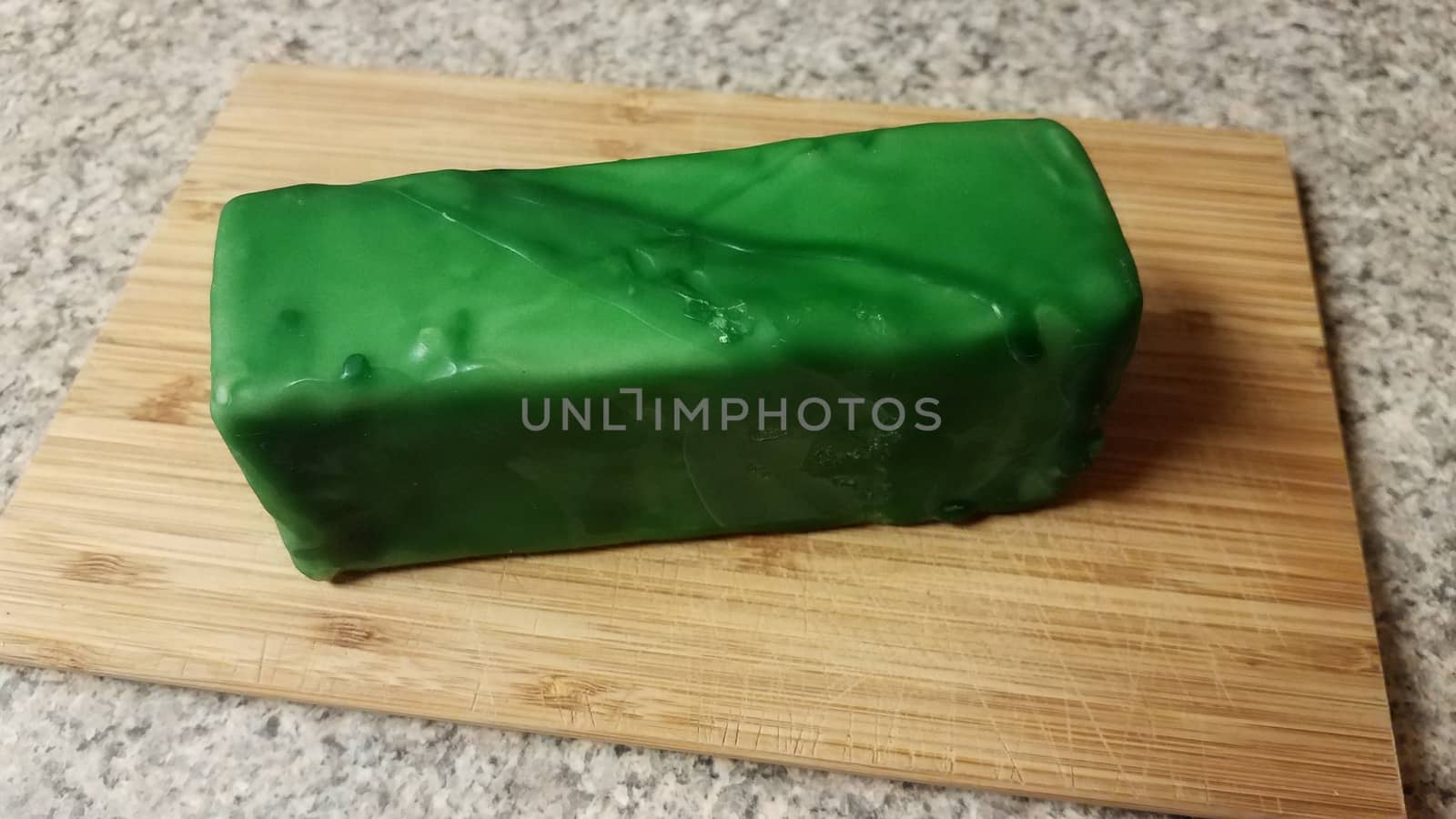 cheese sealed in green wax on wood cutting board by stockphotofan1