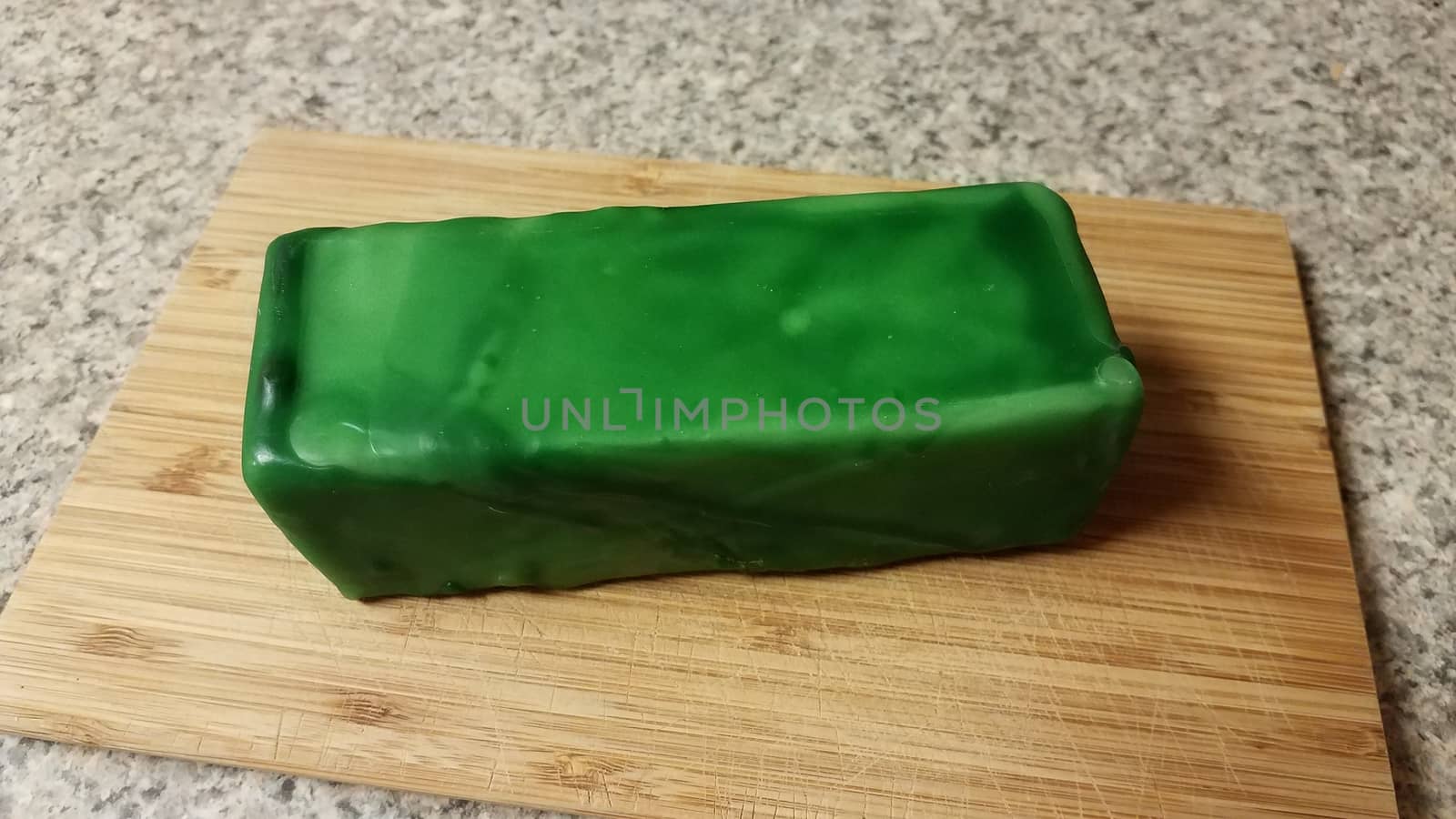 cheese encased or sealed in green wax on wood cutting board