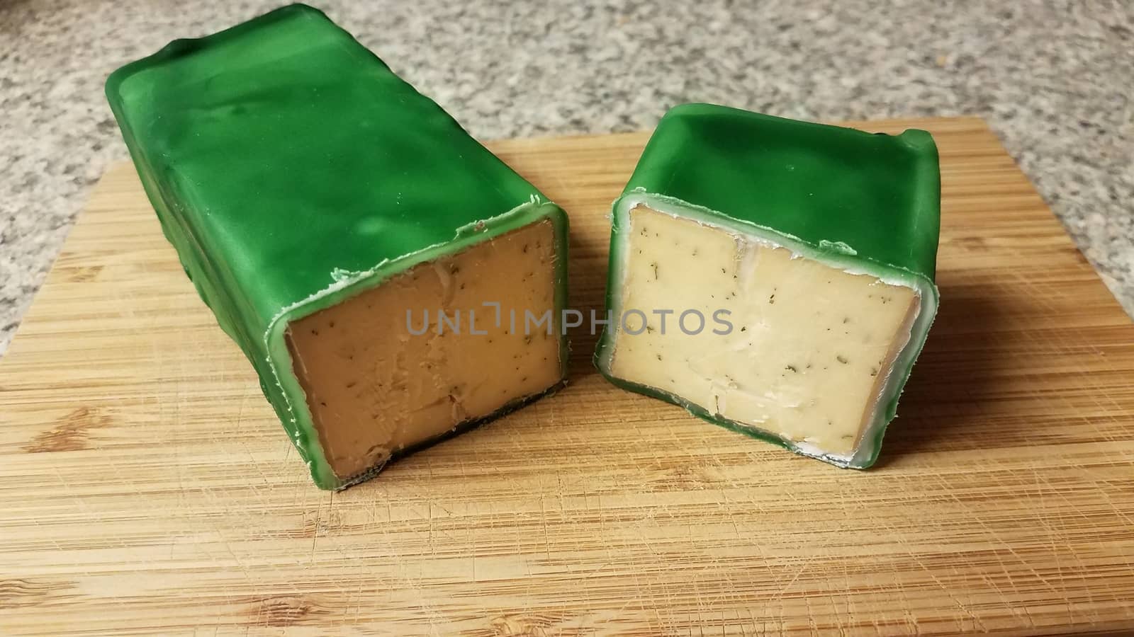 cut cheese encased or sealed in green wax on wood cutting board