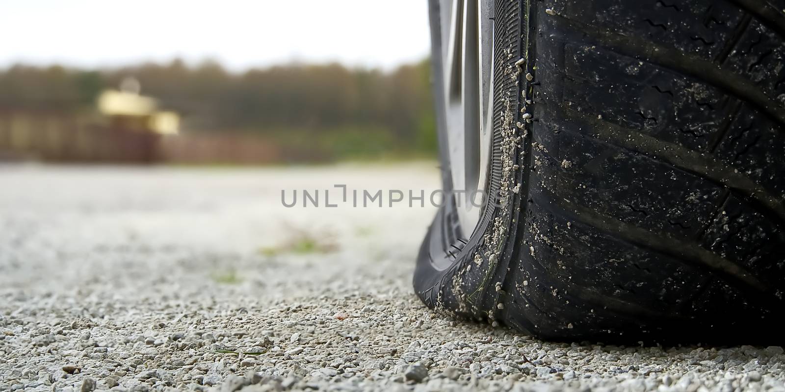 Close-up of Flat rear tire on car. The right rear broken weel. Damaged rear wheels on parking place. by PhotoTime