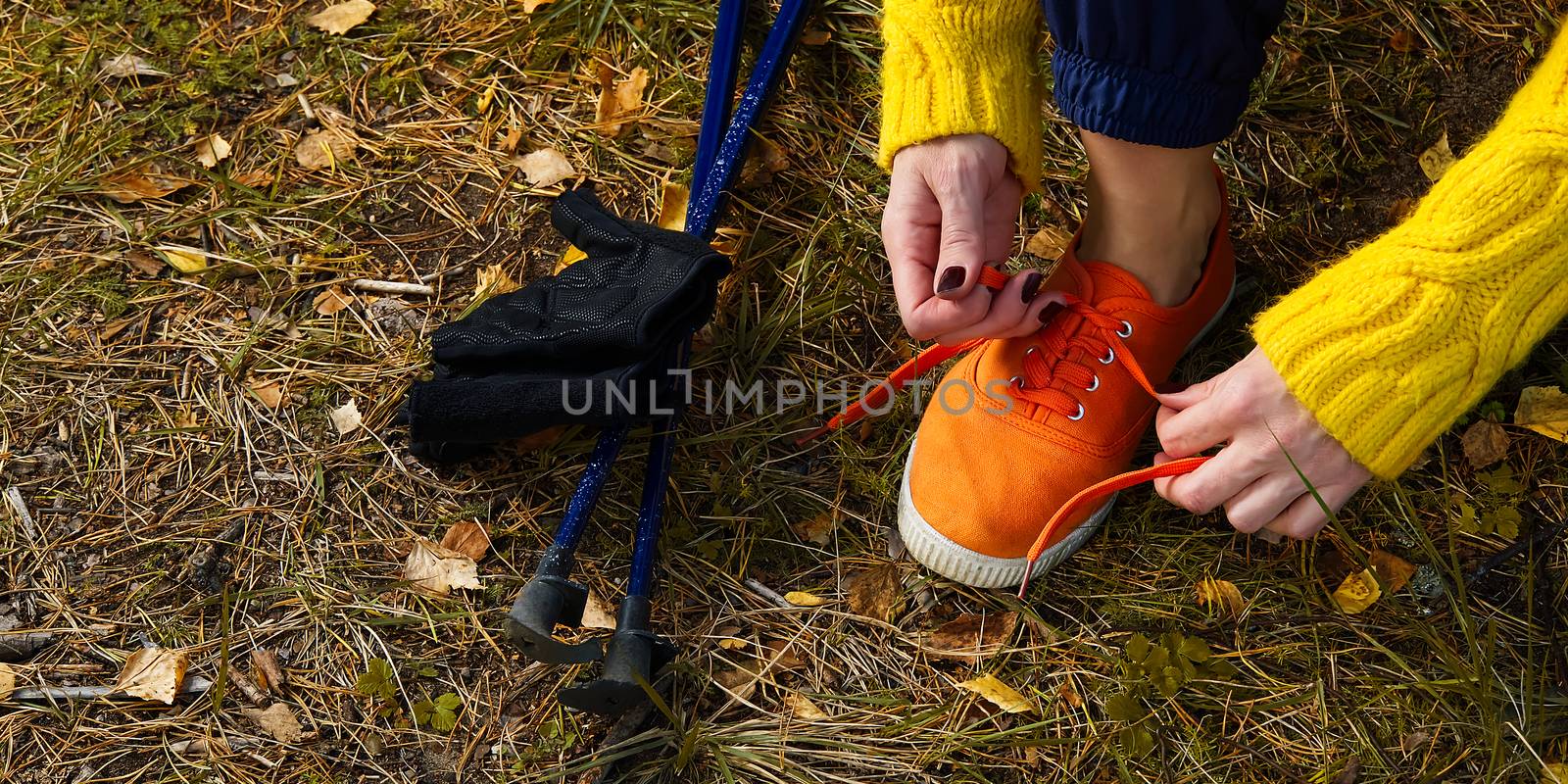 Sporty hiking woman tying shoelaces on her jogging shoes while taking a break after hiking in autumn forest. hiking concept, outdoor lifestyle. by PhotoTime