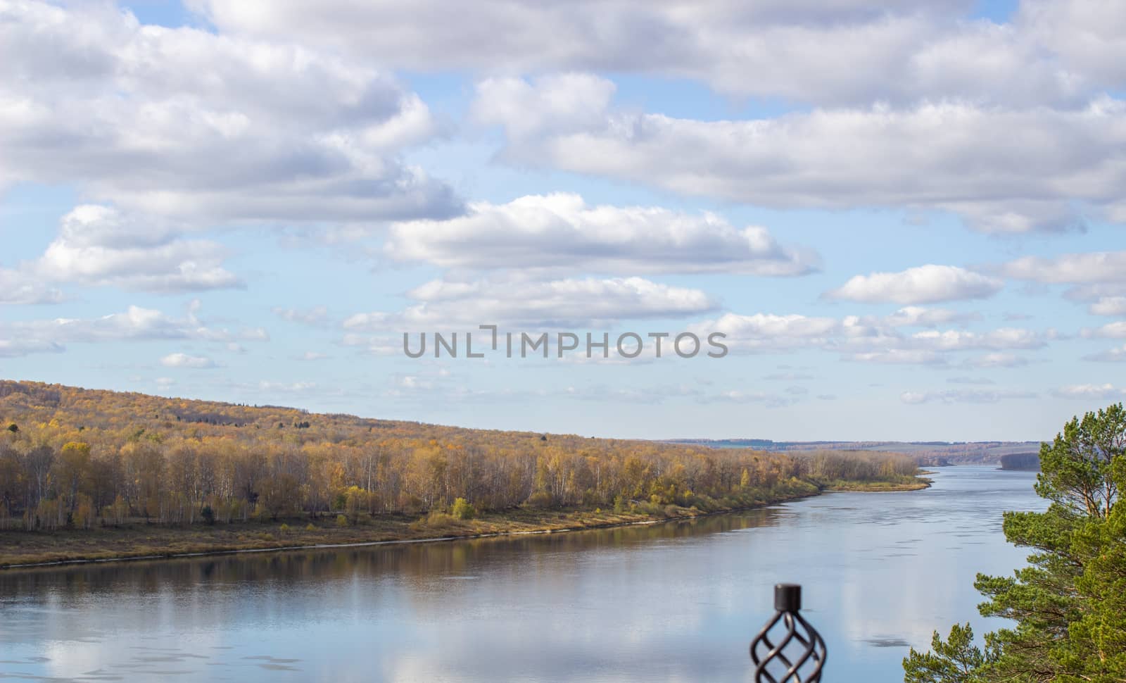 Beautiful, wide river autumn among the woods. Calm and quiet place with autumn colors. Reflection of clouds and forests in water in good weather