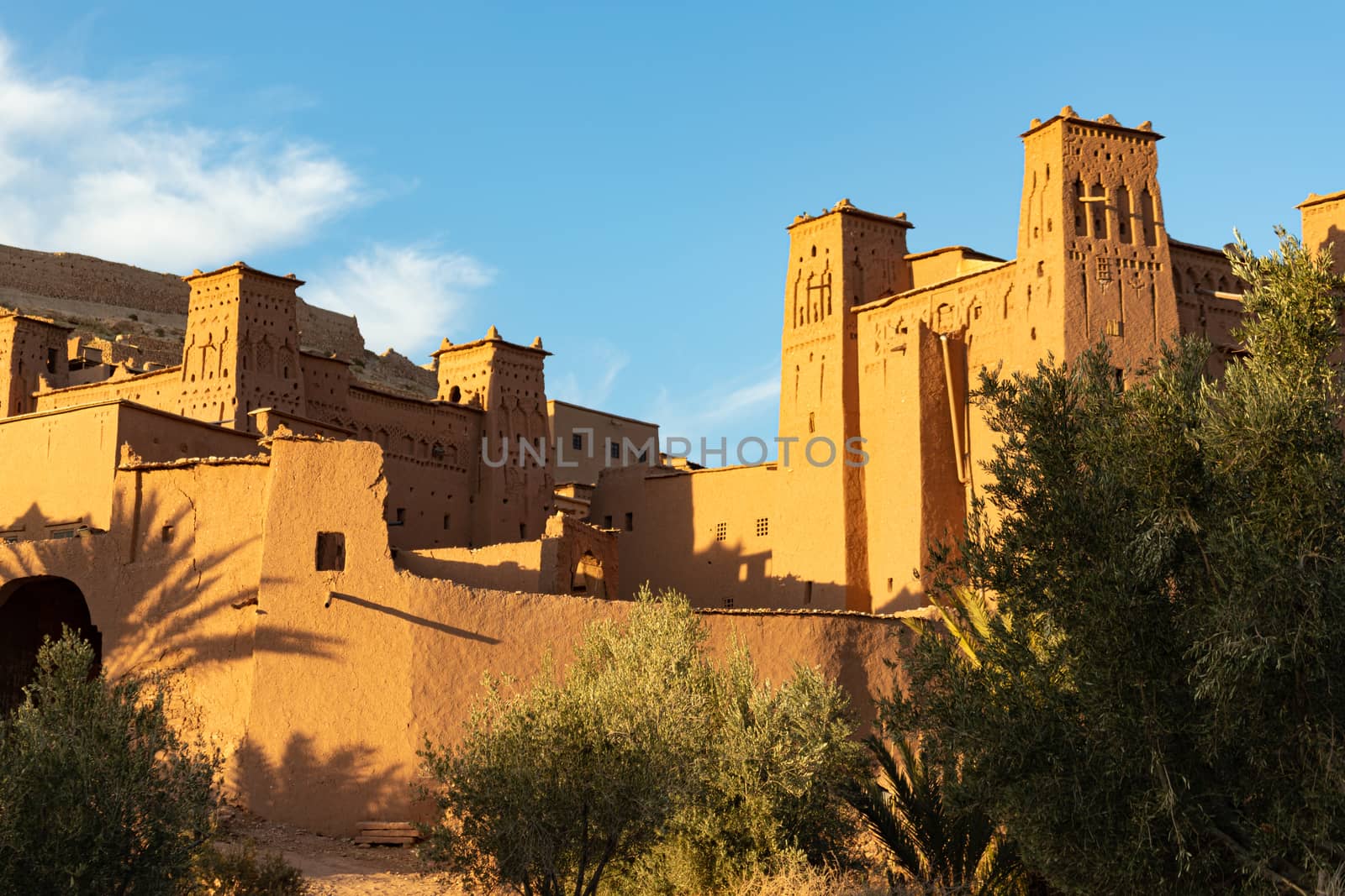 Looking up towards the citadel of Ait Ben Haddou ksar Morocco, ancient fortress that is a Unesco Heritage site. Beautiful late afternoon light with honey, gold coloured mud brick construction the kasbah, or fortified town dates from 11th cent. and is on the former caravan route from the Sahara and Marrakech. The location has been used for many famous movies. High quality photo