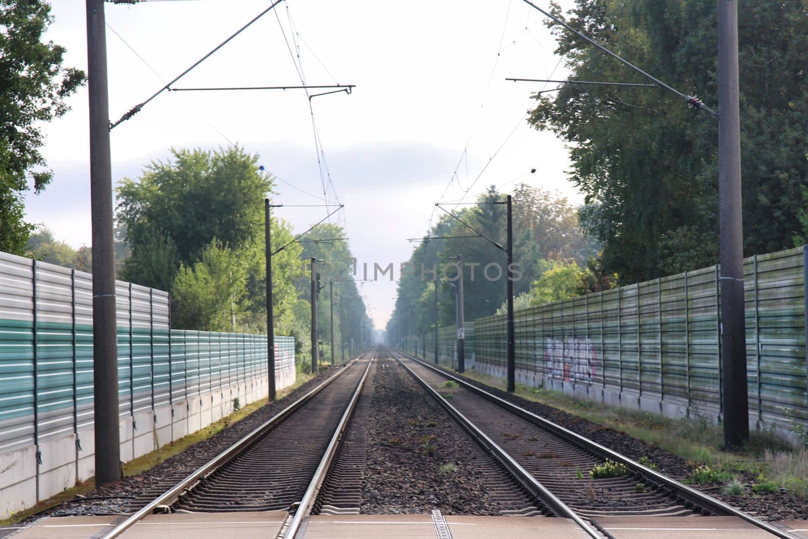Railway tracks with noise protection walls and trees in the background