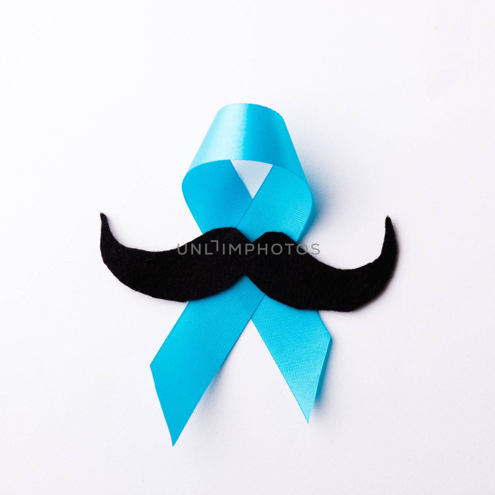 Black mustache paper and light blue ribbon, studio shot isolated on white background, Prostate cancer awareness month, Fathers day, minimal November moustache concept