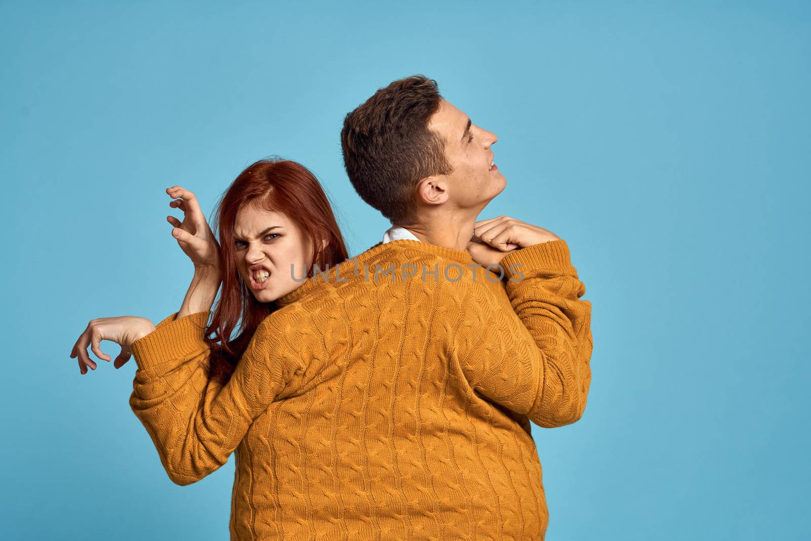 couple in yellow sweater posing against blue background cropped view by SHOTPRIME