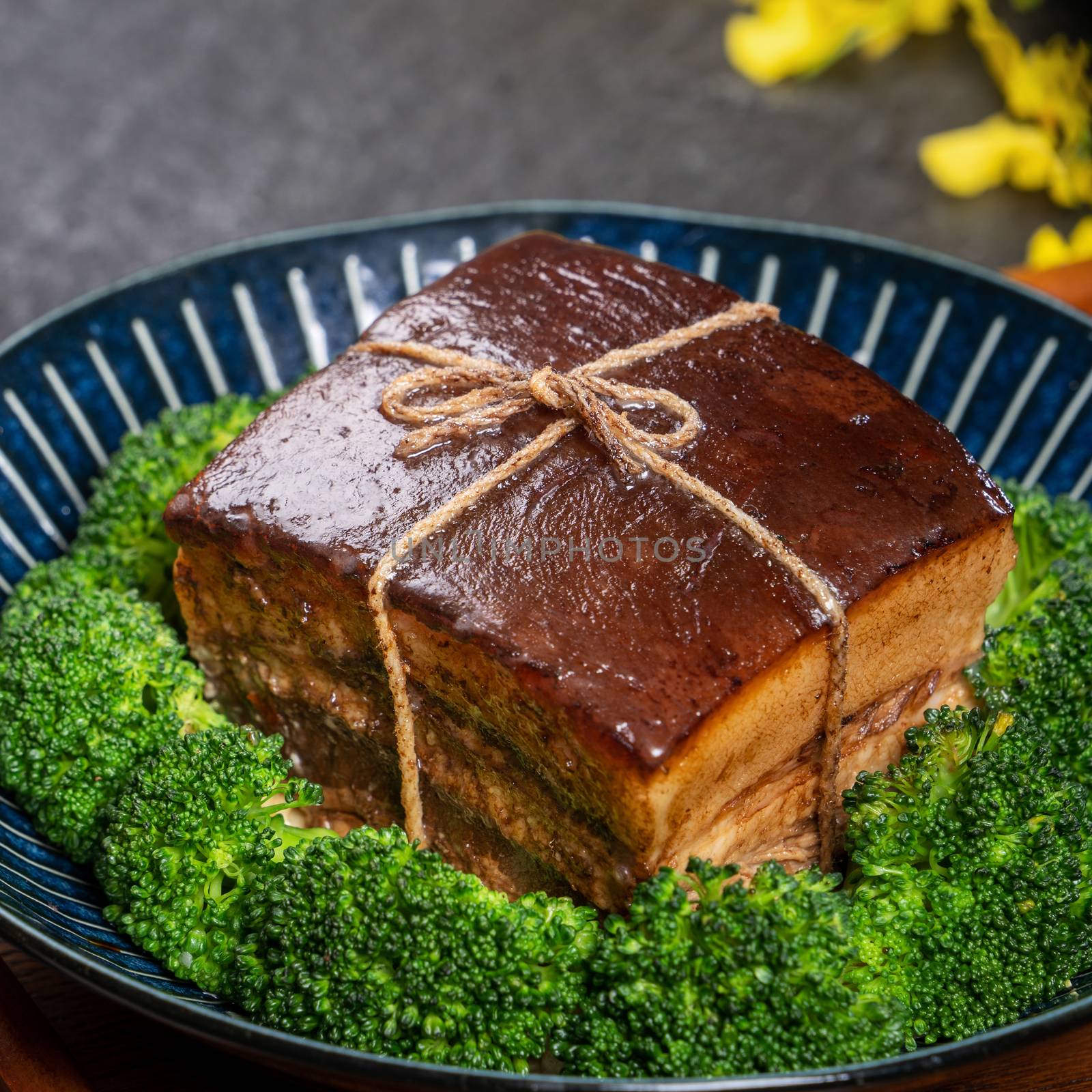 Dong Po Rou (Dongpo pork meat) in a beautiful plate with green vegetable, traditional festive food for Chinese new year cuisine meal, close up.