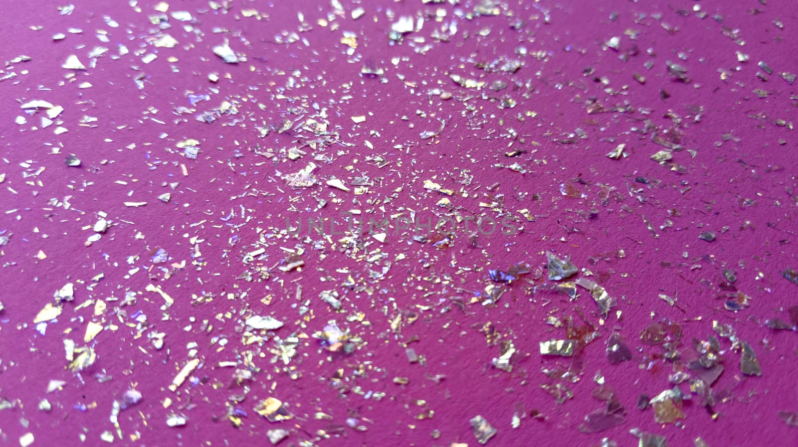 Foil pieces on pink background with multi-colored shine. Abstract fashion macro photo.