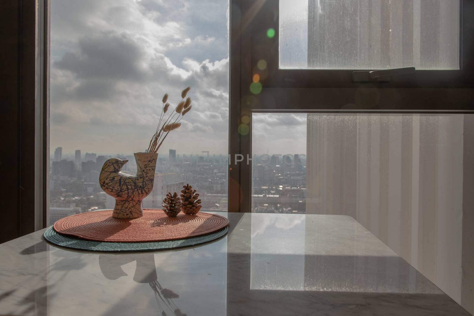 Dried flowers in beautiful ceramic blue vase handmade with two pine cones on table of living room and city view. Home decor. Space for text. Selective focus.
