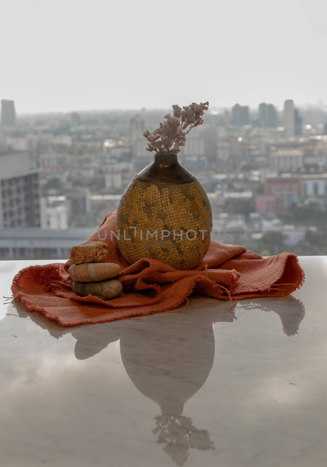 Dried flowers in beautiful ceramic yellow vase handmade on marble table of living room and city view. Home decor. Space for text. Selective focus.