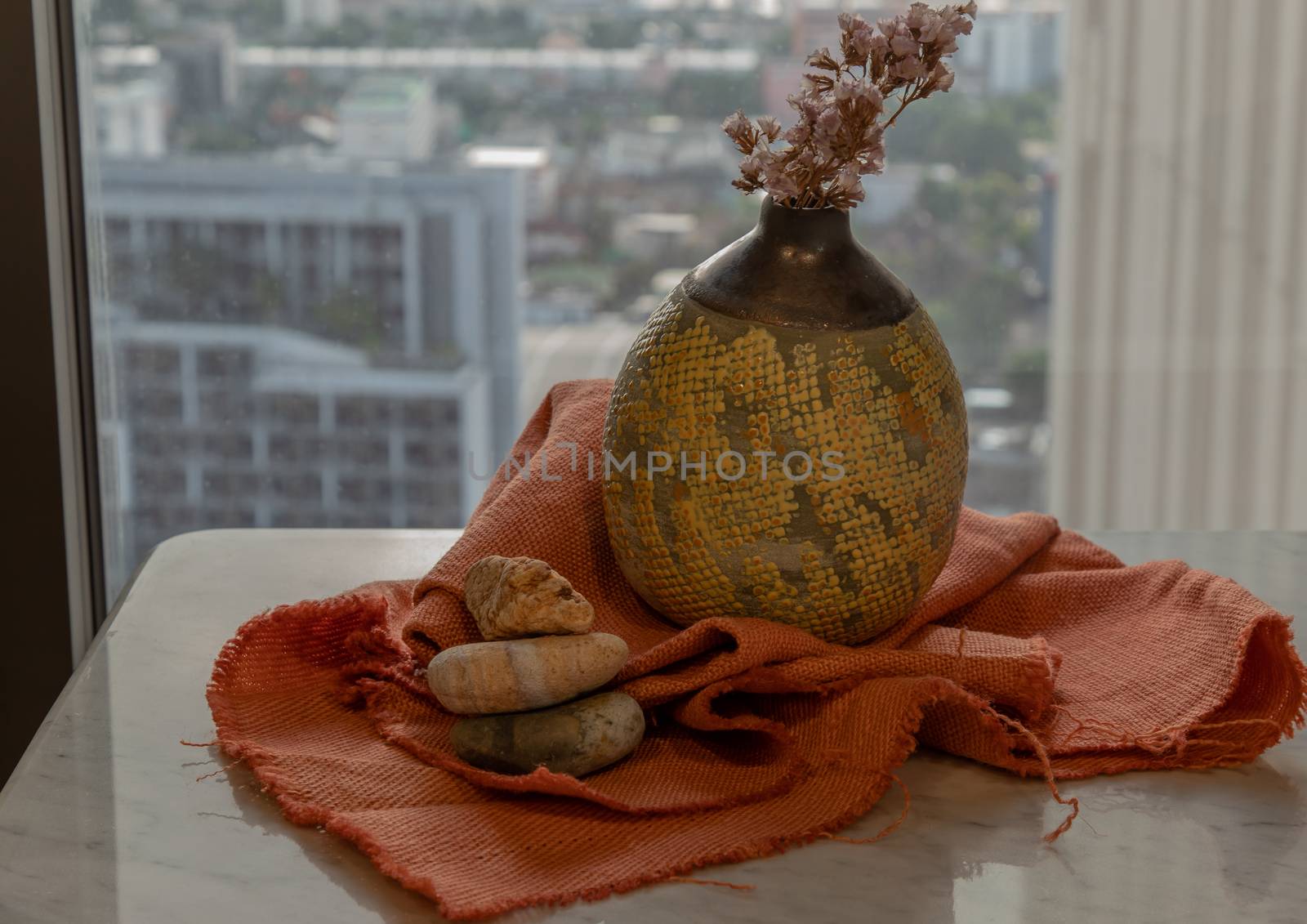 Dried flowers in beautiful ceramic yellow vase handmade on marble table of living room and city view. Home decor. Space for text. Selective focus.