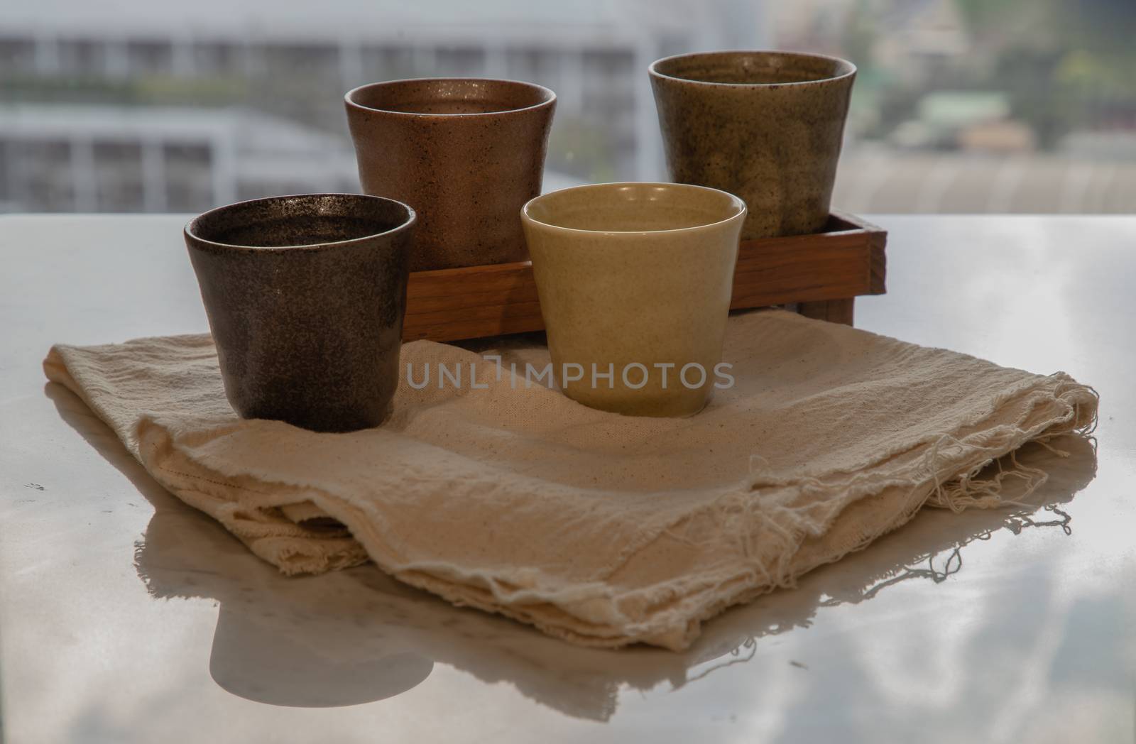 Four ceramics mugs handmade on marble table of living room and city view. Home decor. Space for text. No focus, specifically.