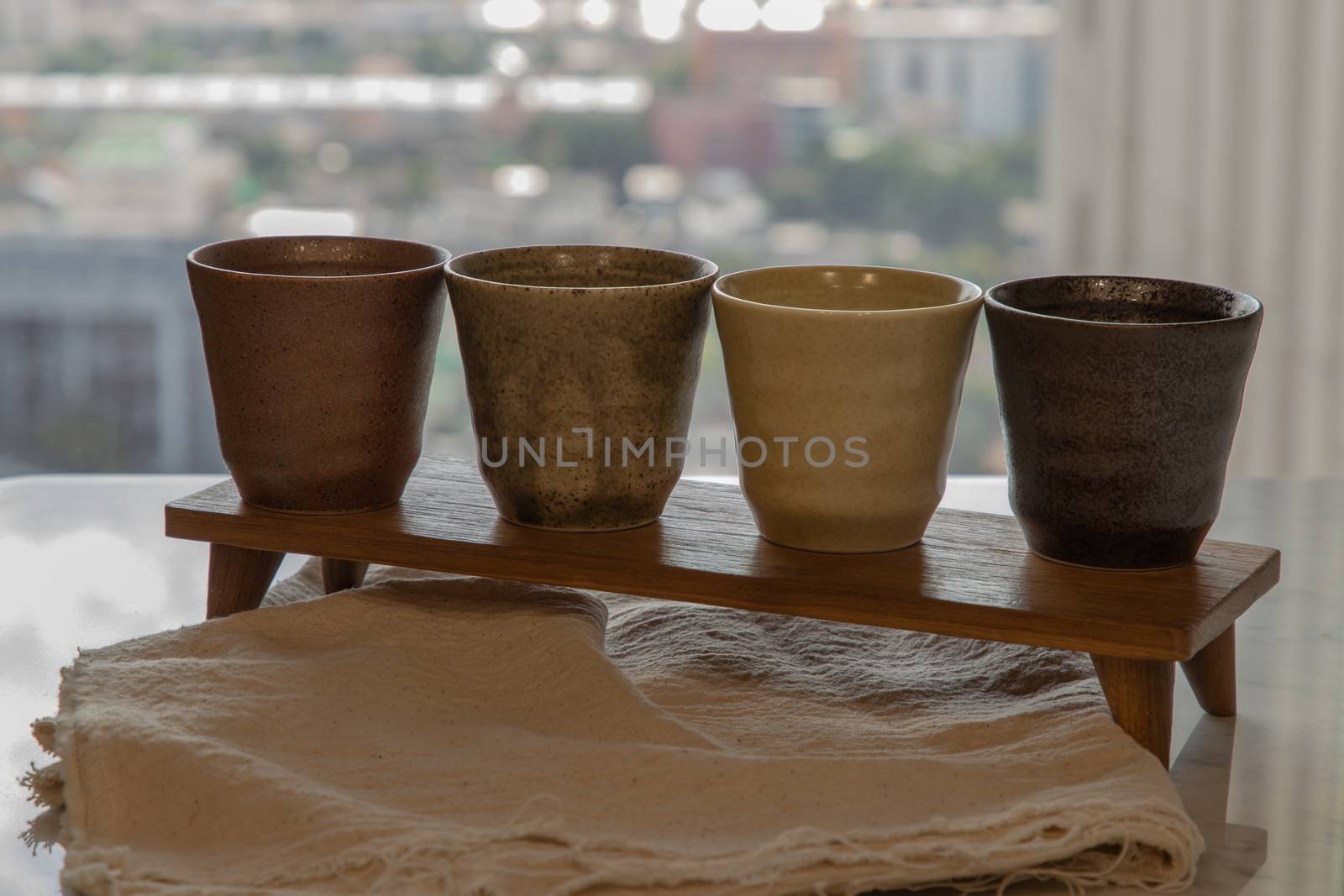 Four ceramics mugs handmade on marble table of living room and city view. Home decor. Space for text. No focus, specifically.