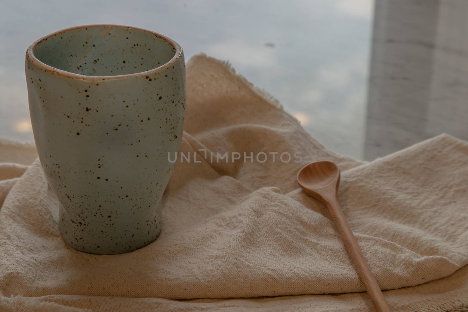 Blue ceramic mug handmade with wooden spoon on marble table of living room and city view. Home decor. Space for text.