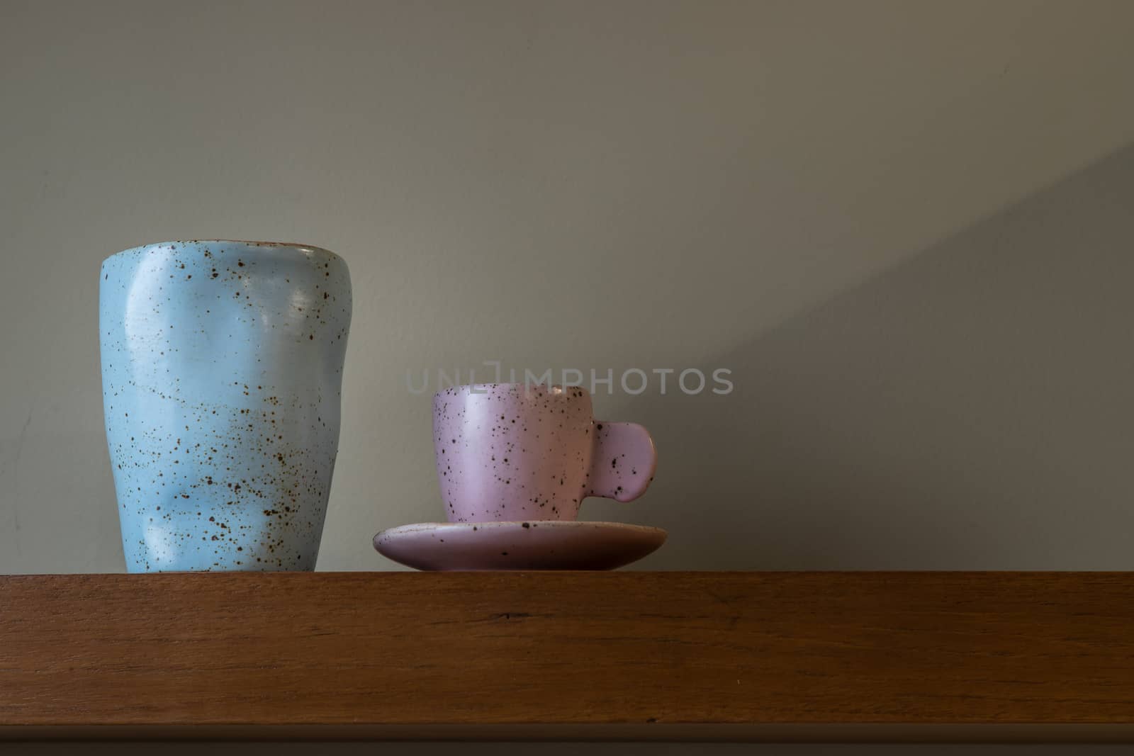 Blue and ceramics mugs handmade on the wooden shelf on wall of living room. Home decor. Space for text. No focus, specifically.