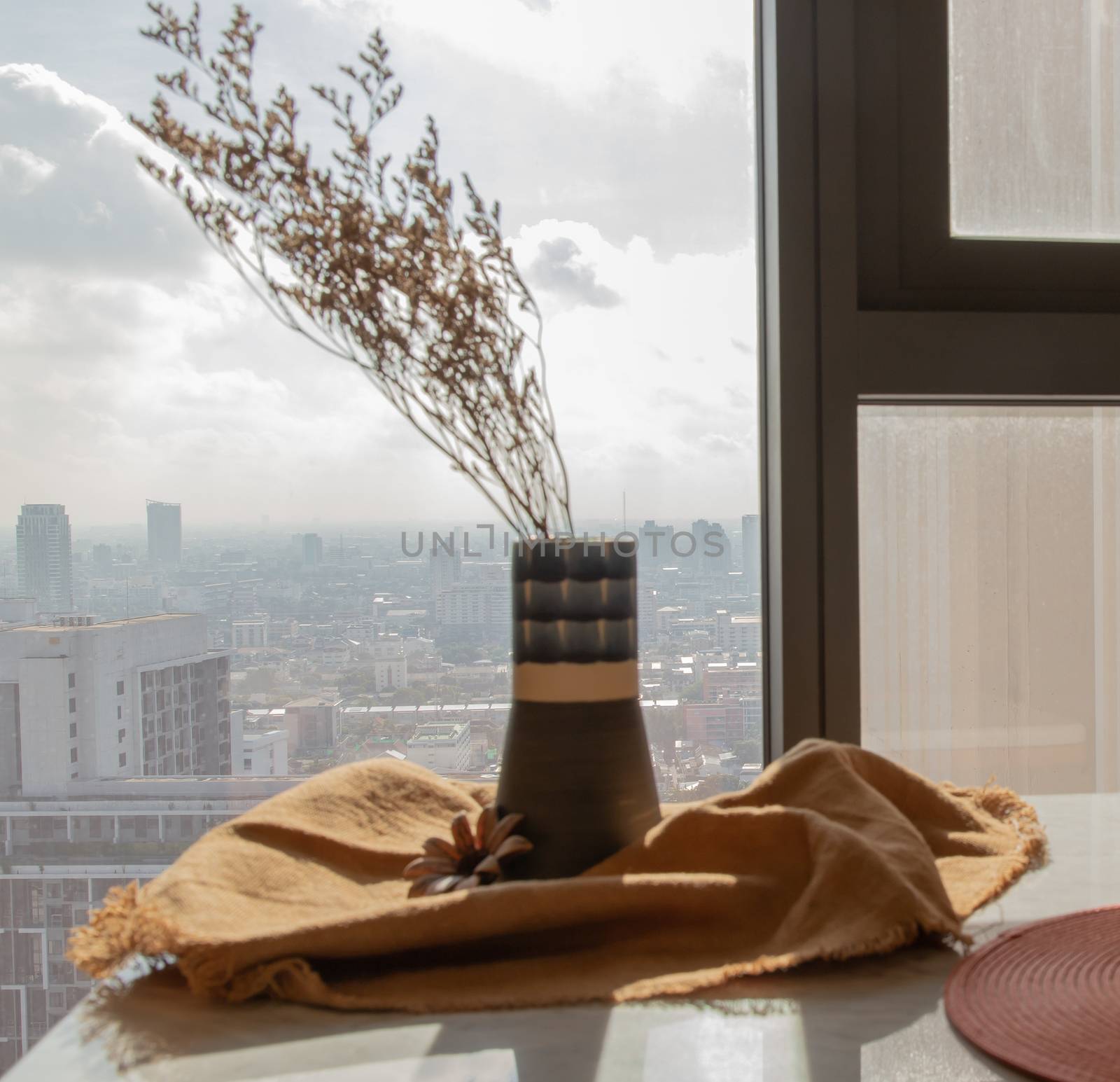 Dried flowers in beautiful ceramic blue vase handmade on table of living room and city view. Home decor. Space for text. Selective focus.