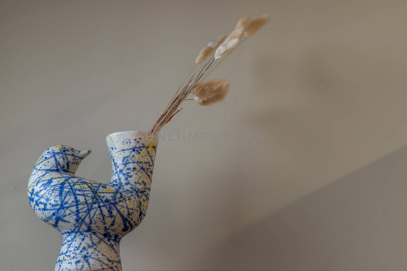 Dried flowers in beautiful ceramic blue vase on wall of living room. Home decor. Space for text. Selective focus.