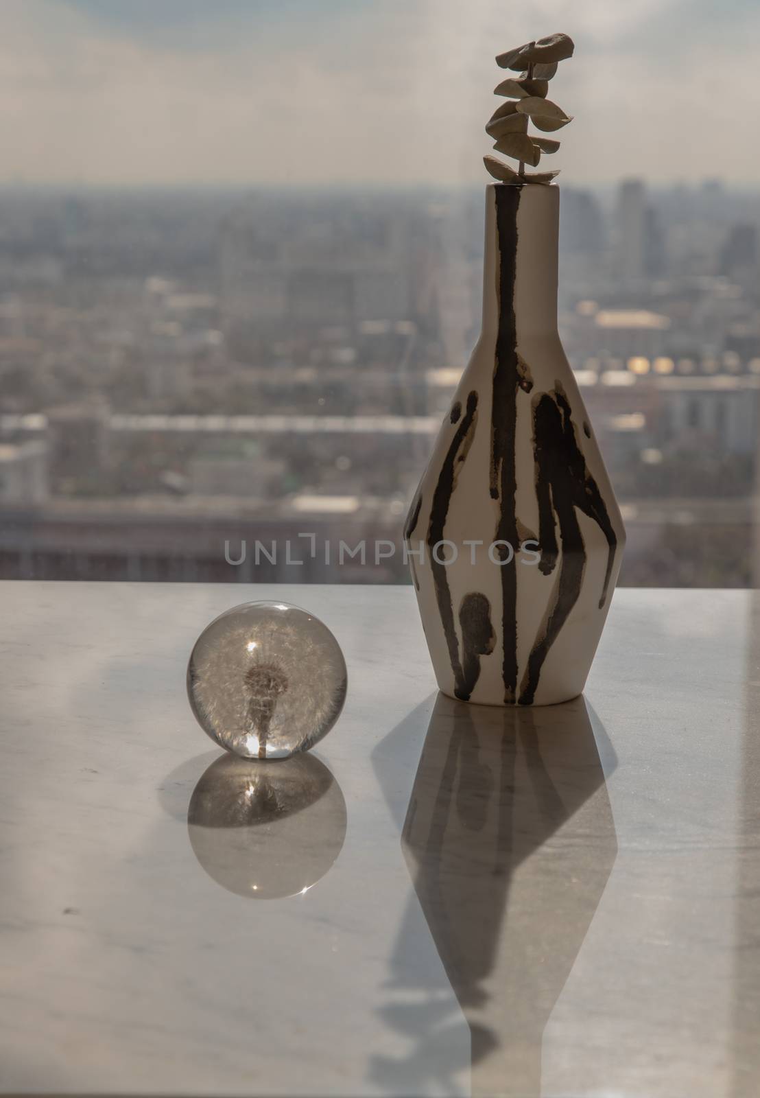 Dried flowers in beautiful ceramic black and white vase handmade with glass paper weight on marble table of living room and city view. Home decor. Space for text. Selective focus.