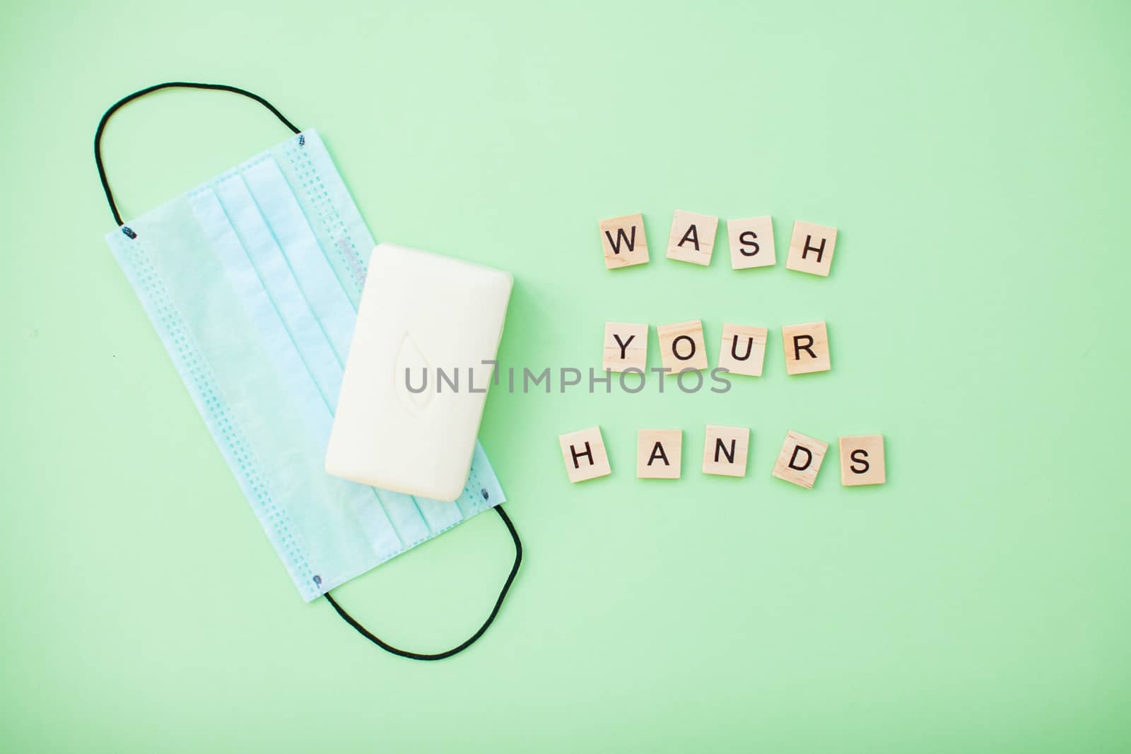 inscription from wooden blocks wash your hands and soap and protective medical mask on a light green background