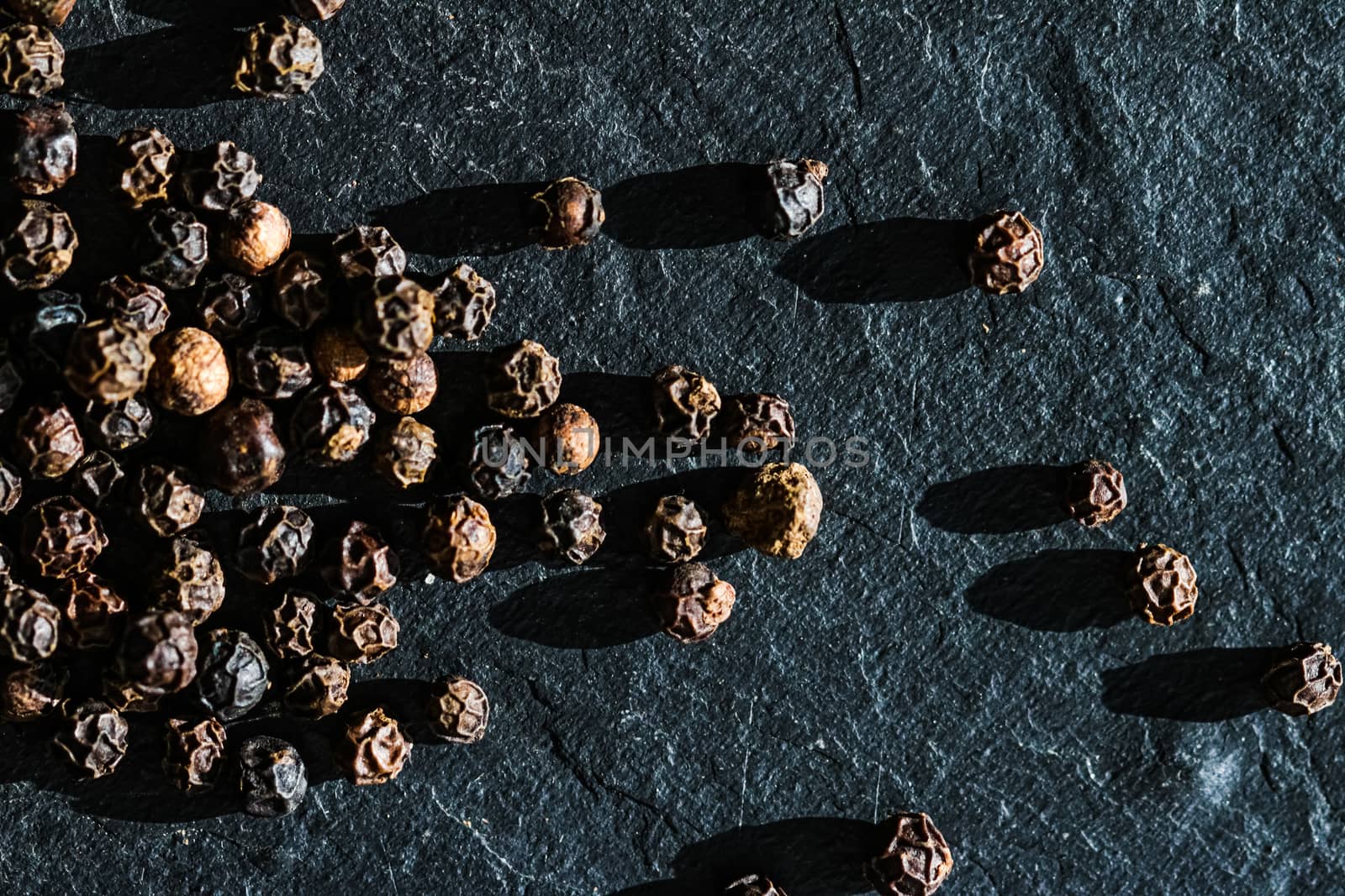Black pepper closeup on luxury stone background as flat lay, dry food spices and recipe ingredients