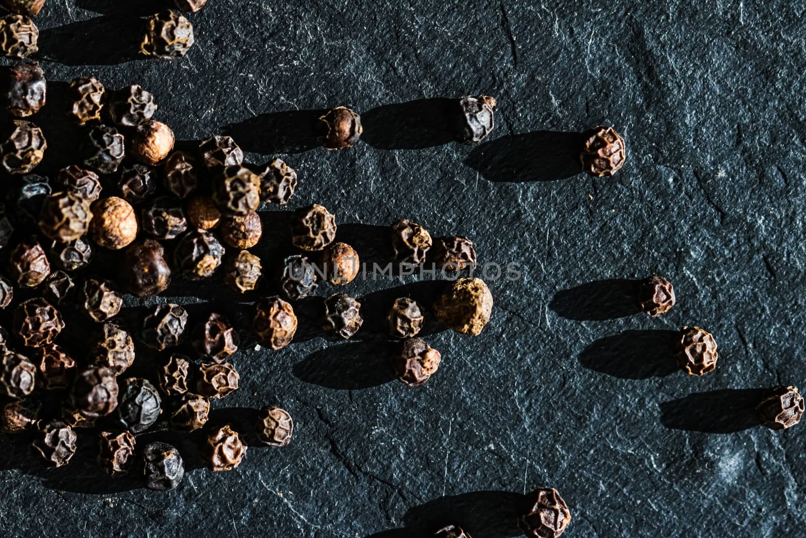 Black pepper closeup on luxury stone background as flat lay, dry food spices and recipe ingredient by Anneleven