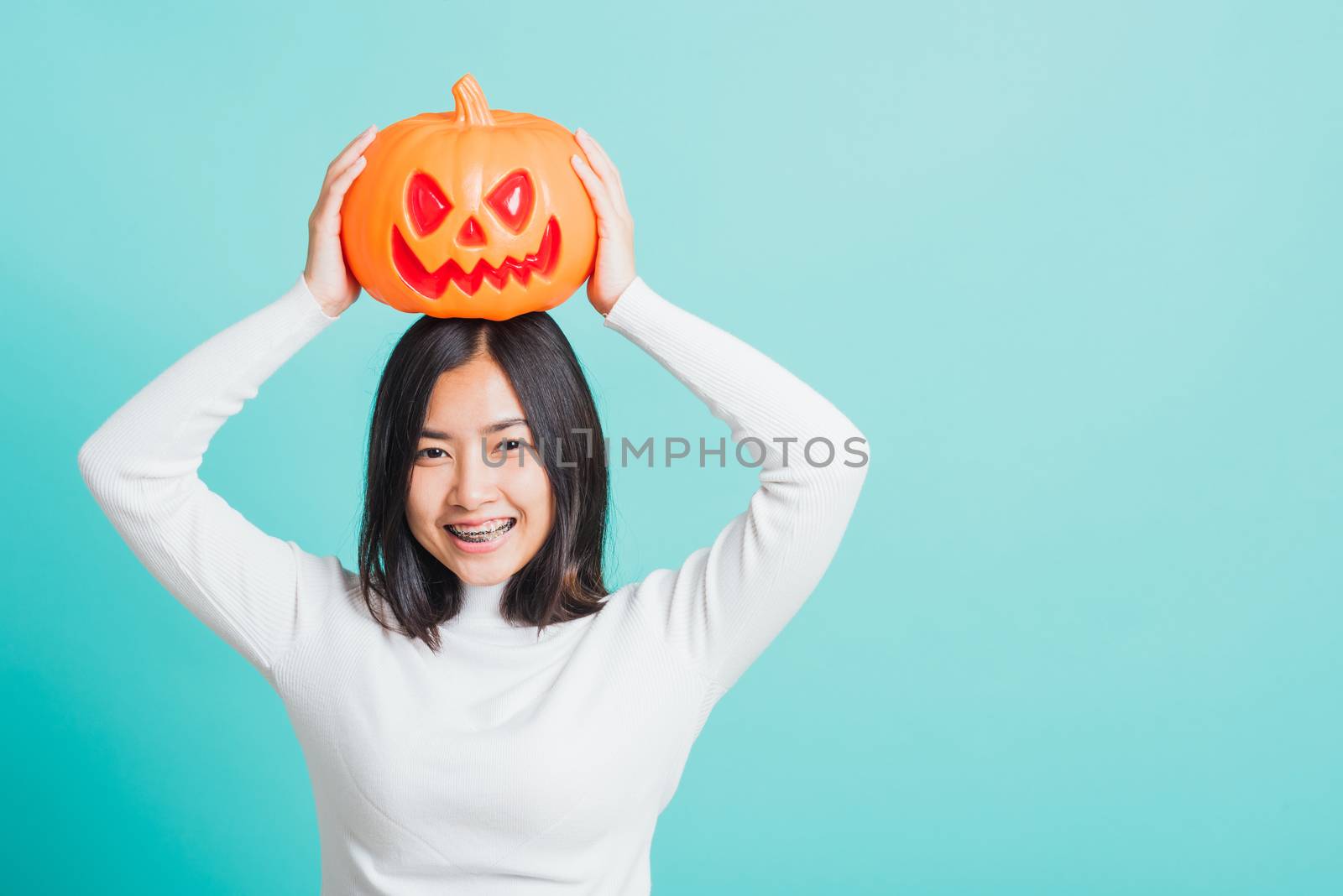 woman holding orange model pumpkins and put it on the head by Sorapop