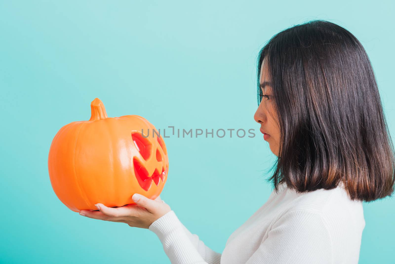 woman holding orange model pumpkins and looking it by Sorapop