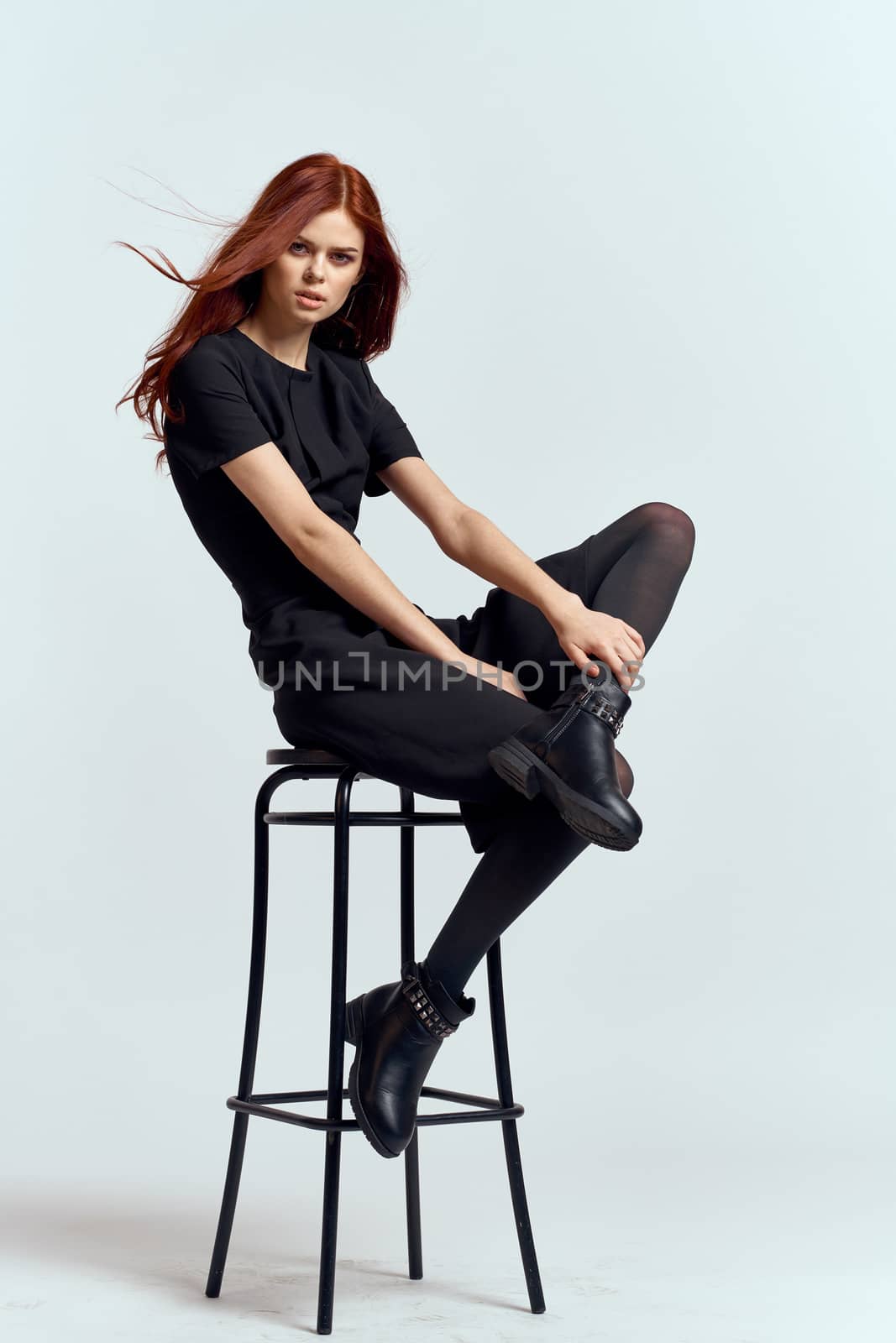 woman high chair indoors full length black dress red hair model boots. High quality photo