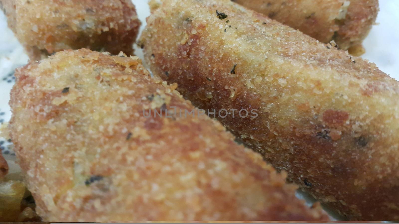 Closeup perspective view of home made spicy and delicious croquettes served in ceramic plate over wooden floor