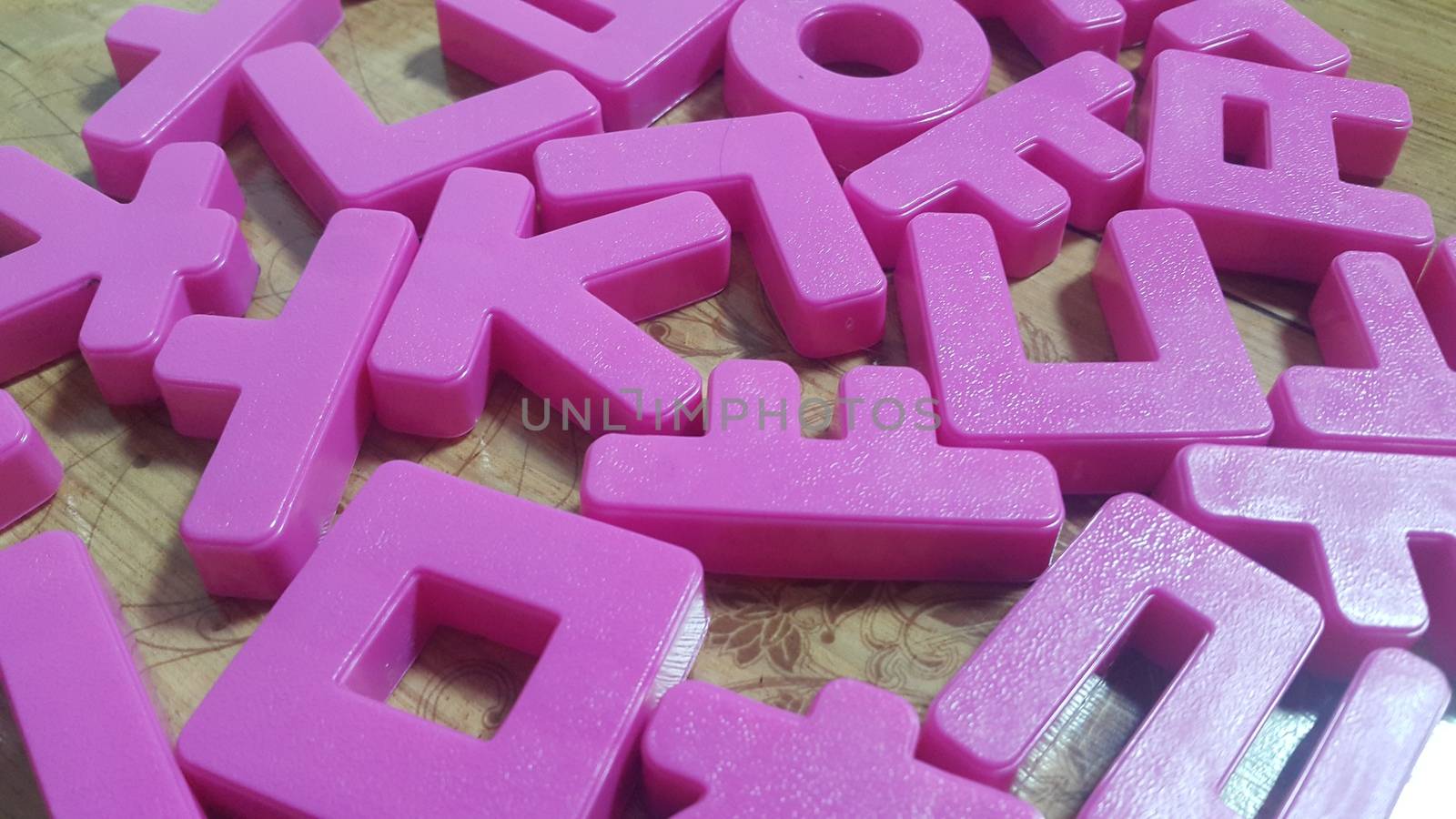 Set of plastic alphabet letters placed on a wooden floor by Photochowk