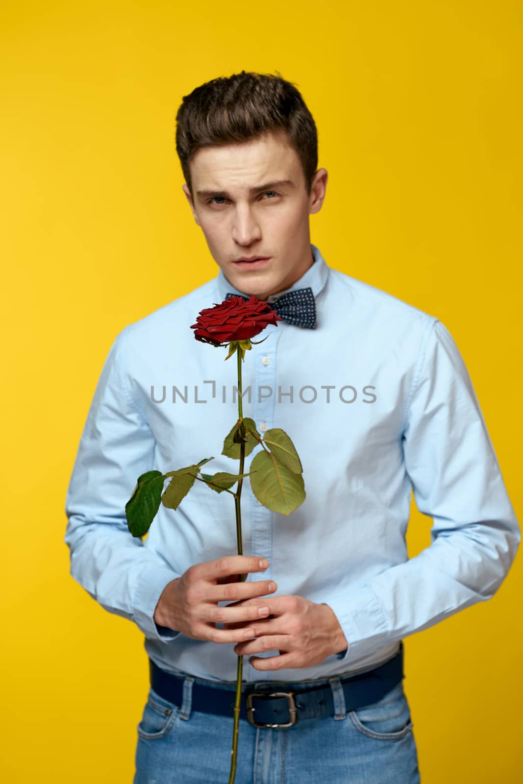 Gentleman in shirt and bow tie around his neck yellow background red rose by SHOTPRIME