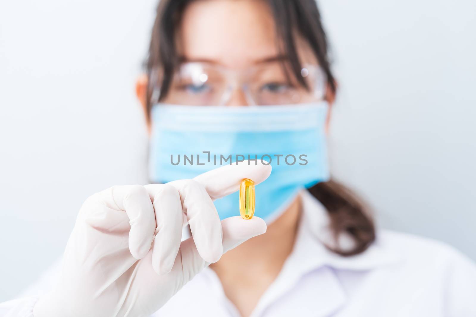 Close up Scientist holding Omega 3 capsule in labcoat  by stoonn