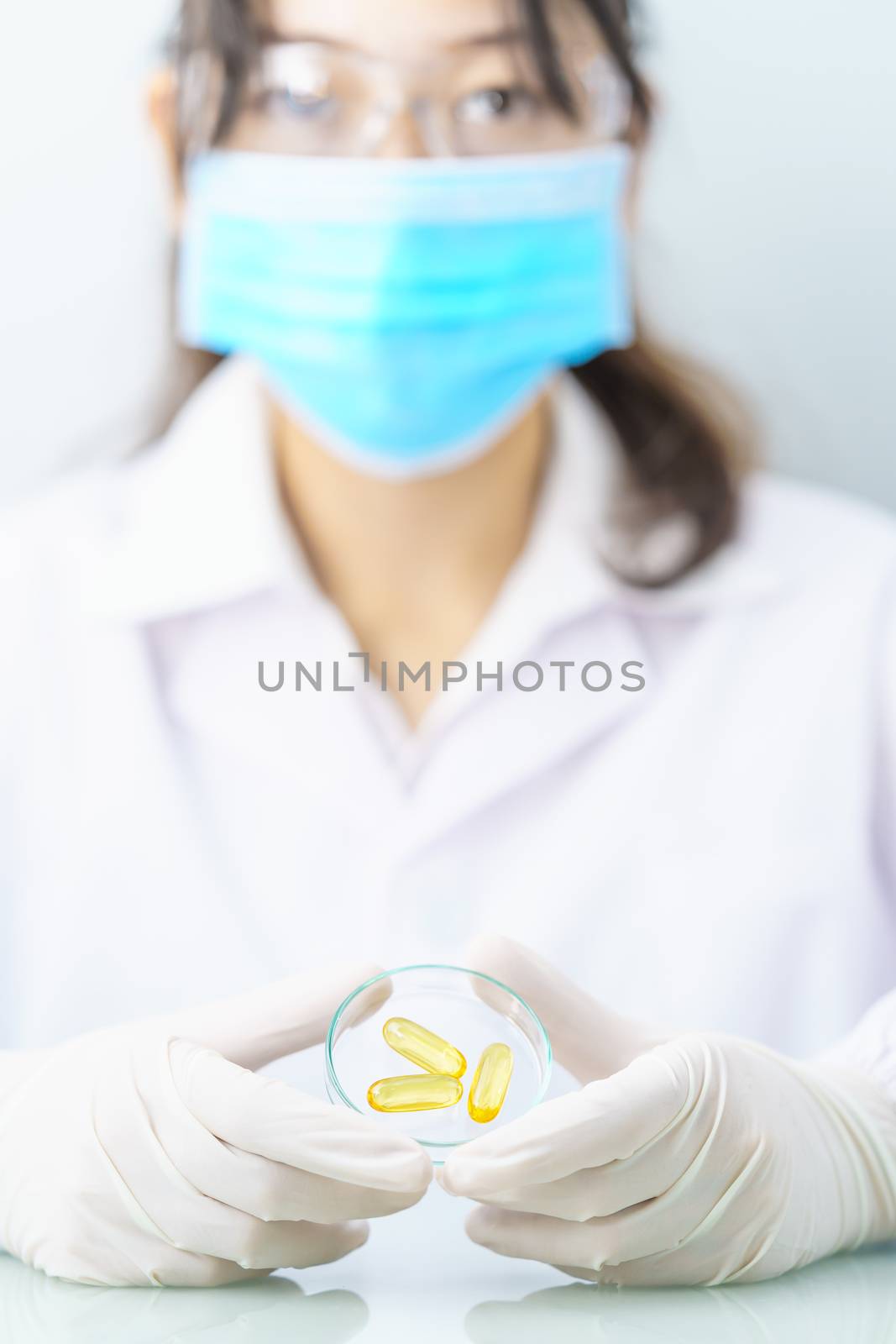 Scientist holding Omega 3 capsule in labcoat  by stoonn