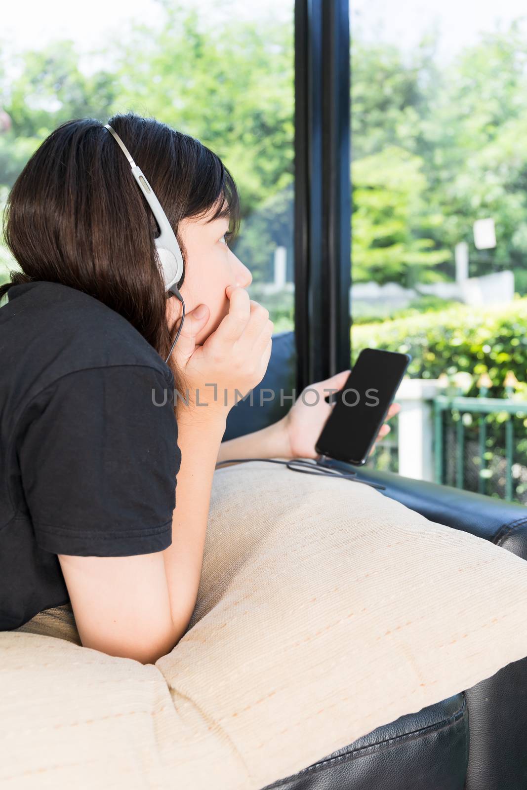 Young girl listening to music from mobile phone in living room by stoonn