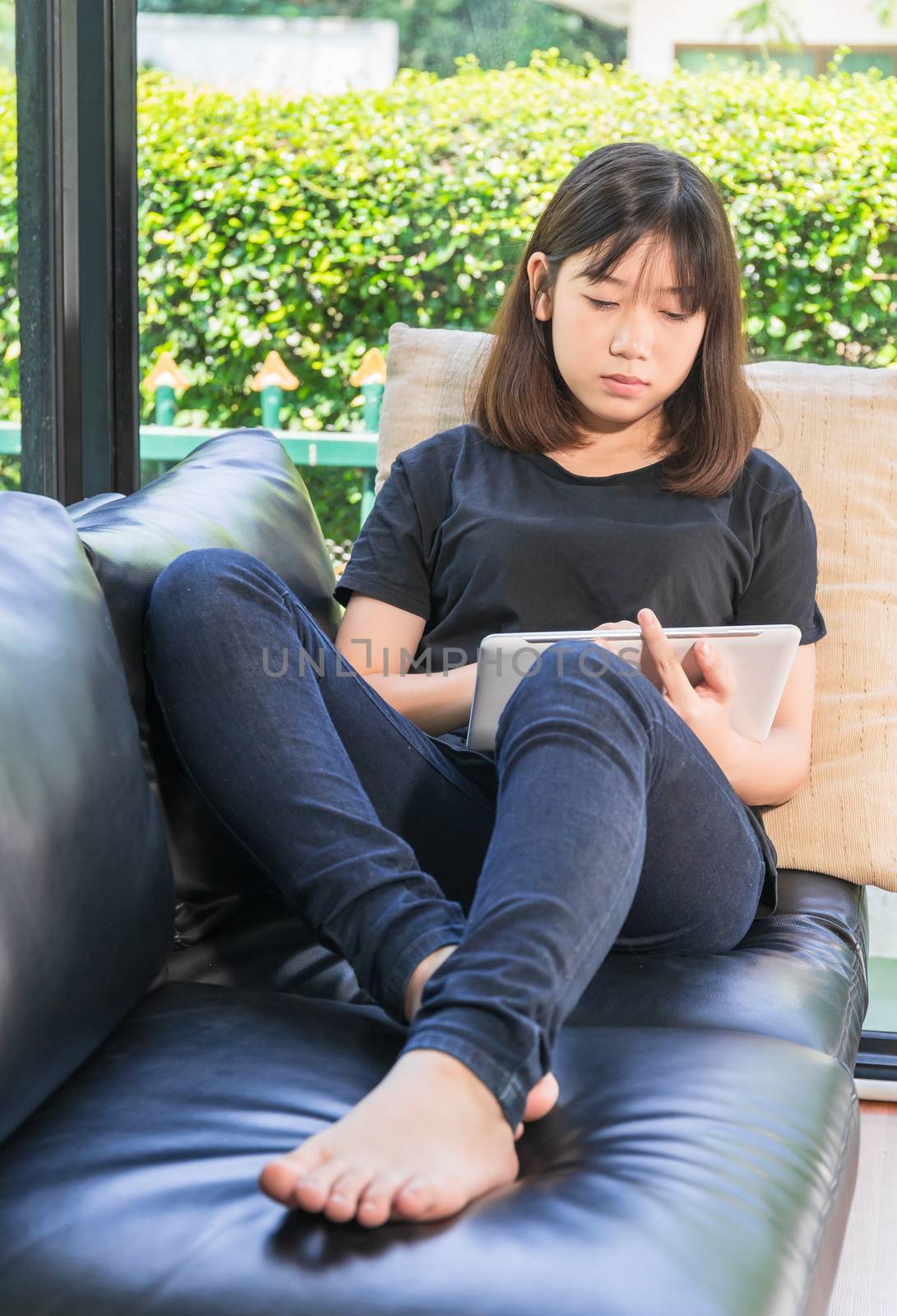 Young girl studying online from digital tablet in living room by stoonn