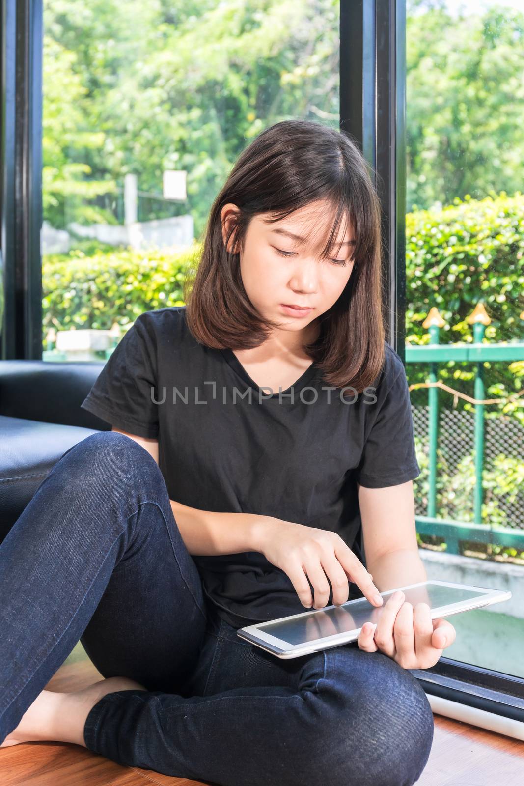 Young girl studying online from digital tablet on the sofai n living room at home